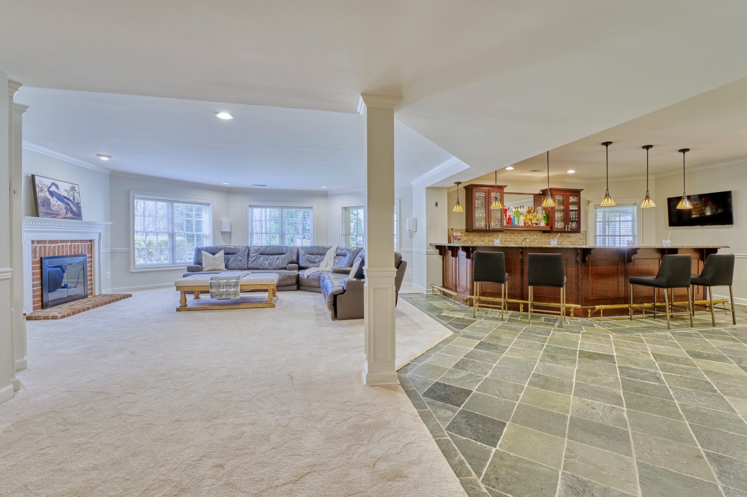 Professional interior photo of 17087 Bold Venture Drive, Leesburg - showing the finished basement with a large bar area to the right and carpeted media area to the left - perfect for gameday!