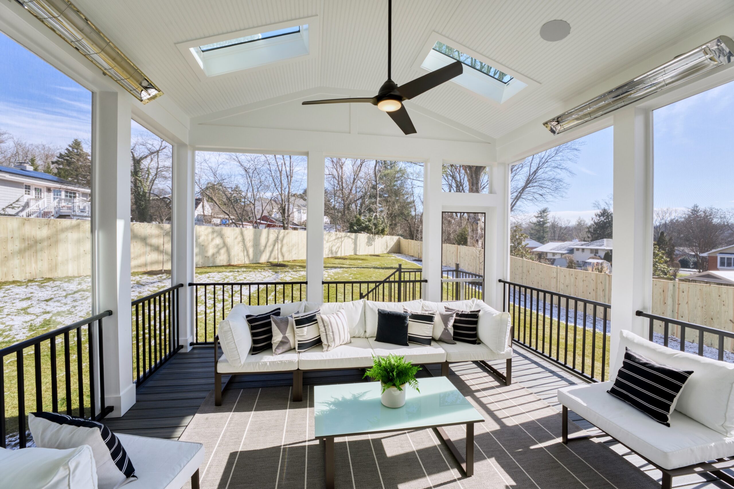 Professional interior photo of 1624 Dempsey St, McLean, VA - showing the inside of the screened porch looking out toward the fenced backyard, skylights, heaters, and ceiling fan