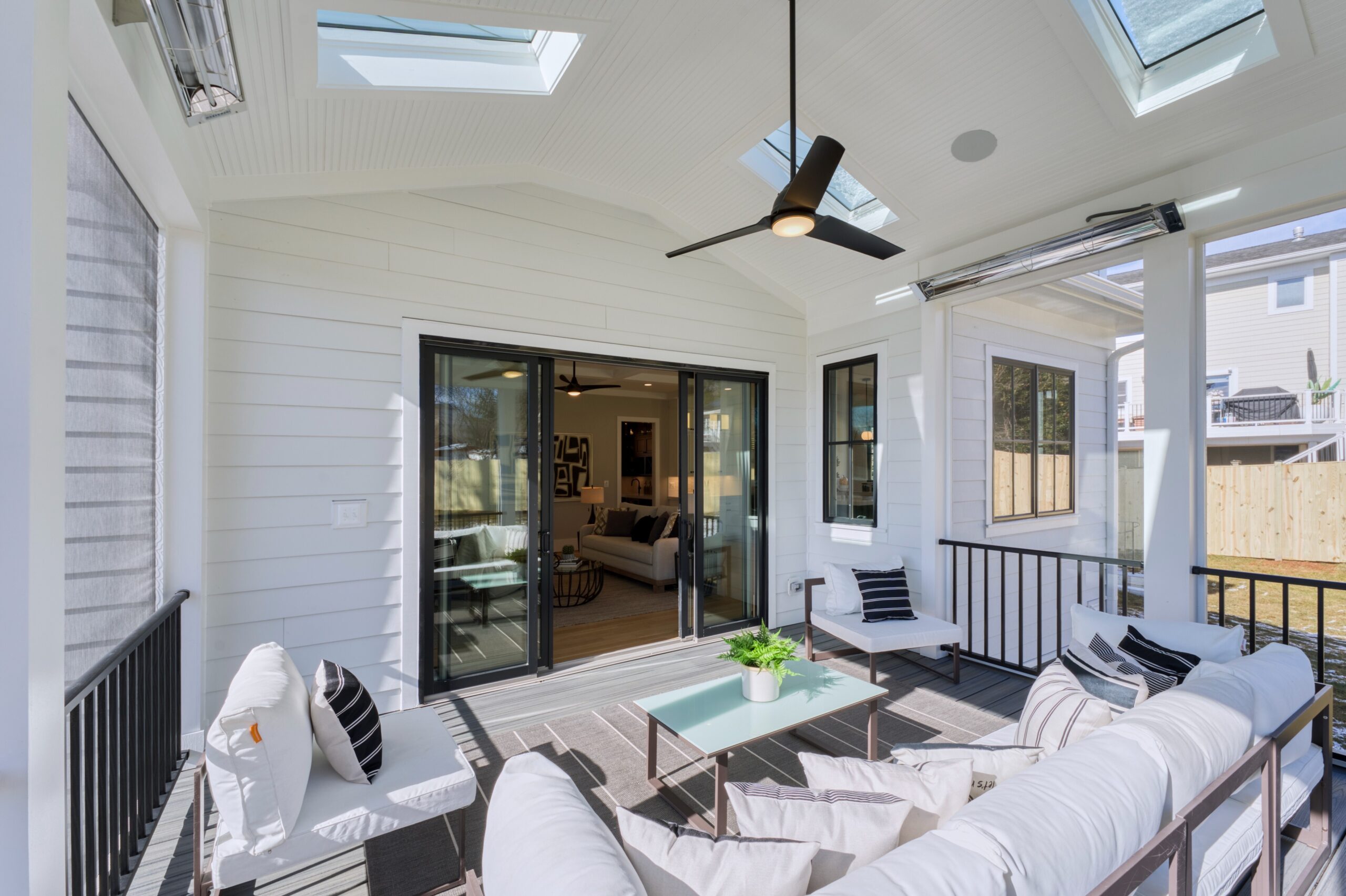 Professional interior photo of 1624 Dempsey St, McLean, VA - showing the inside of the screened porch looking toward the door to the main house, skylights, heaters, and ceiling fan