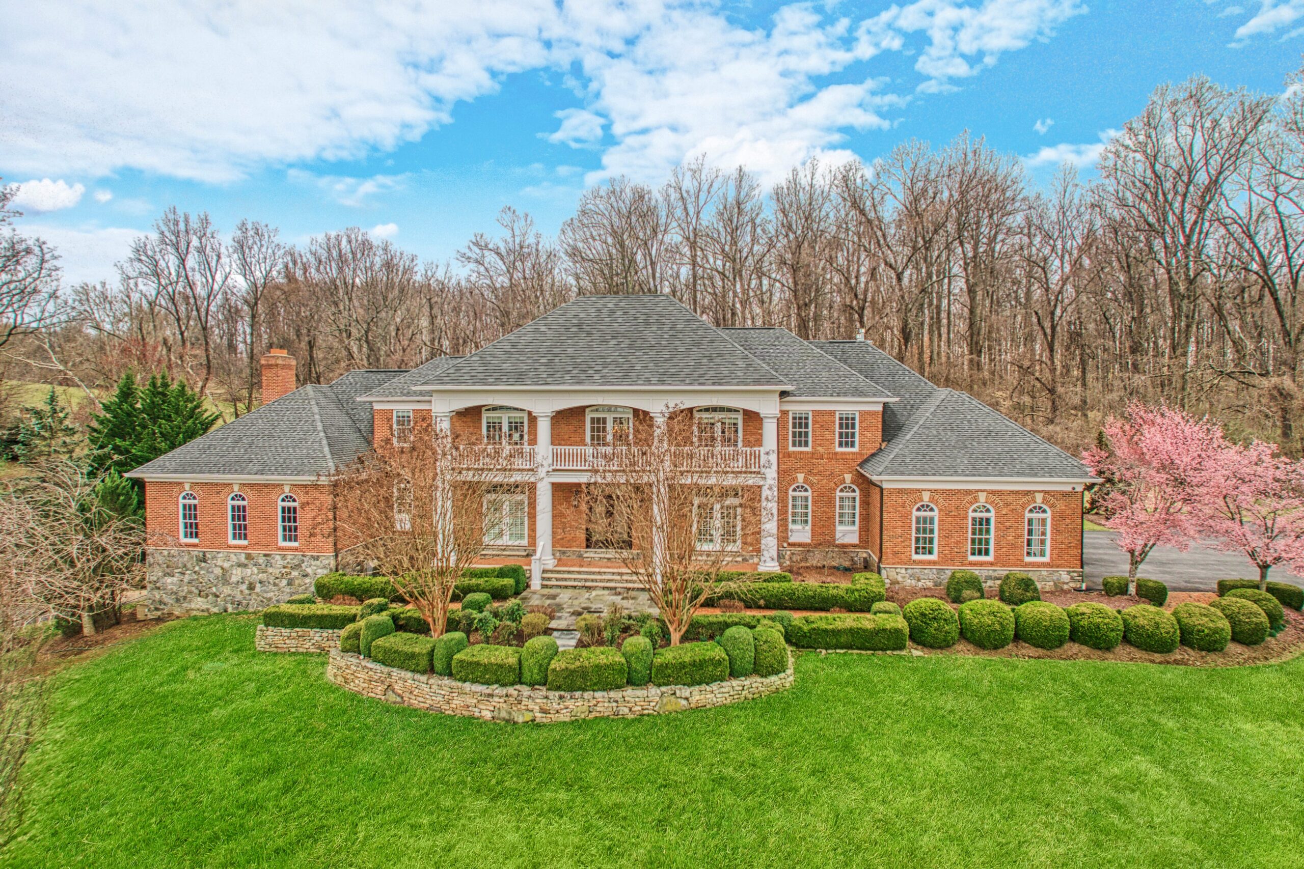 Exterior professional photo of 40573 Spectacular Bid Place - showing the front brick facade of the Georgian-style manor home taken from an drone