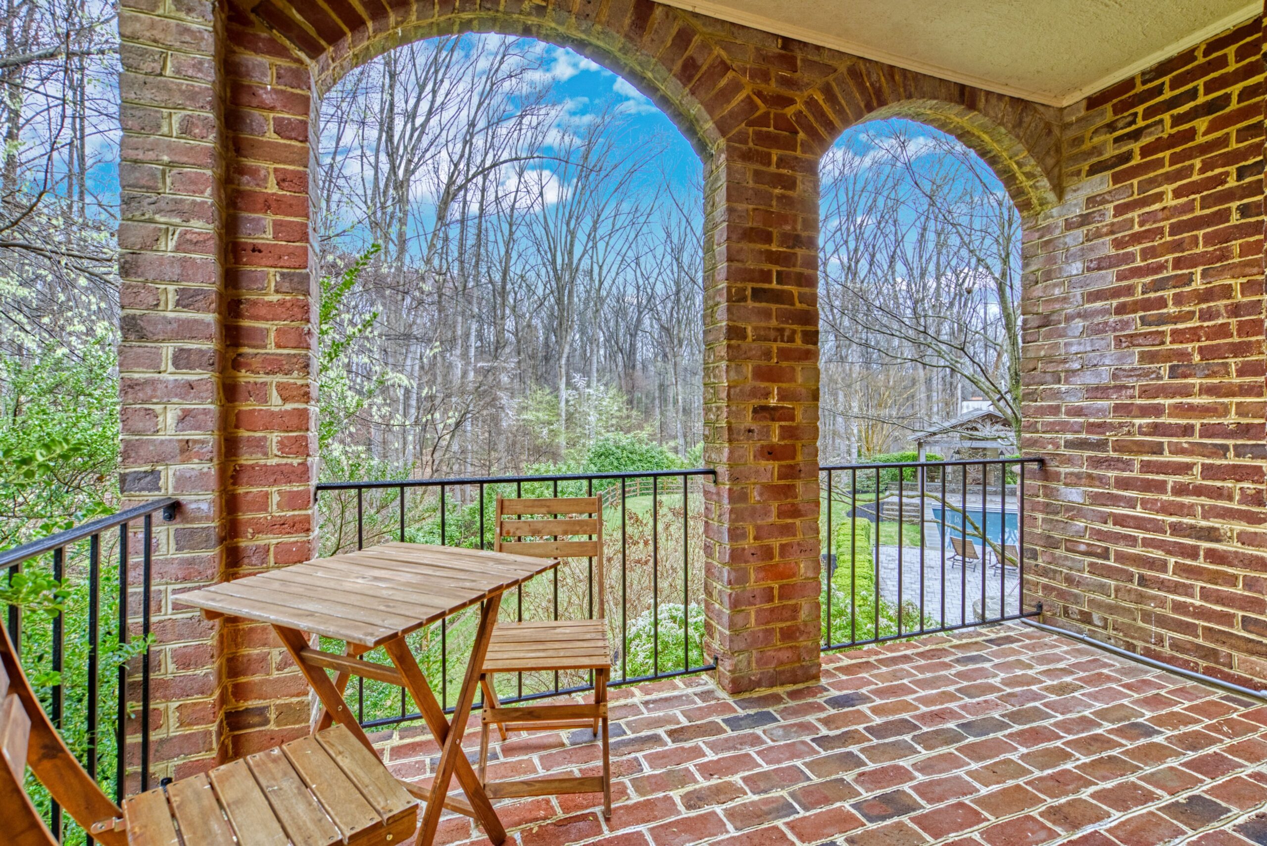 Professional exterior photo of 718 Potomac Knolls Dr - showing the inside of one of the brick terraces, glimpsing the pool in the background