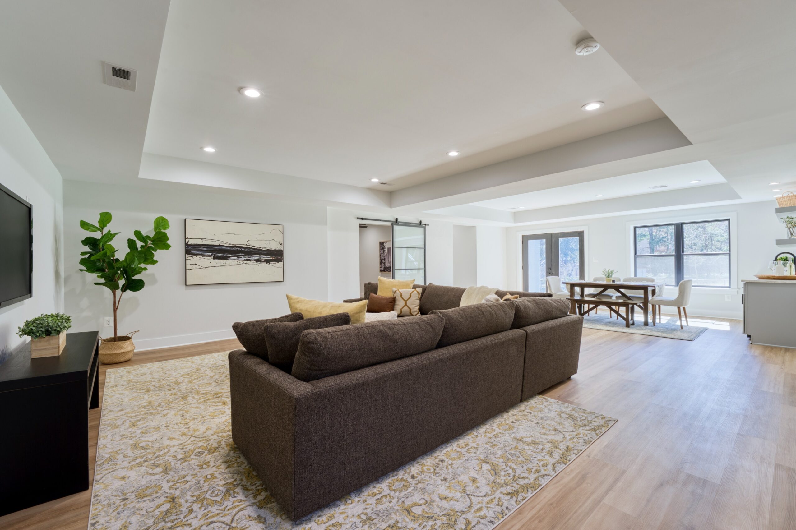 Professional interior photo of Custom New Home 1416 S Greenbrier St - showing the casual living room on the lower level with LVP woodlike floors and trey ceiling