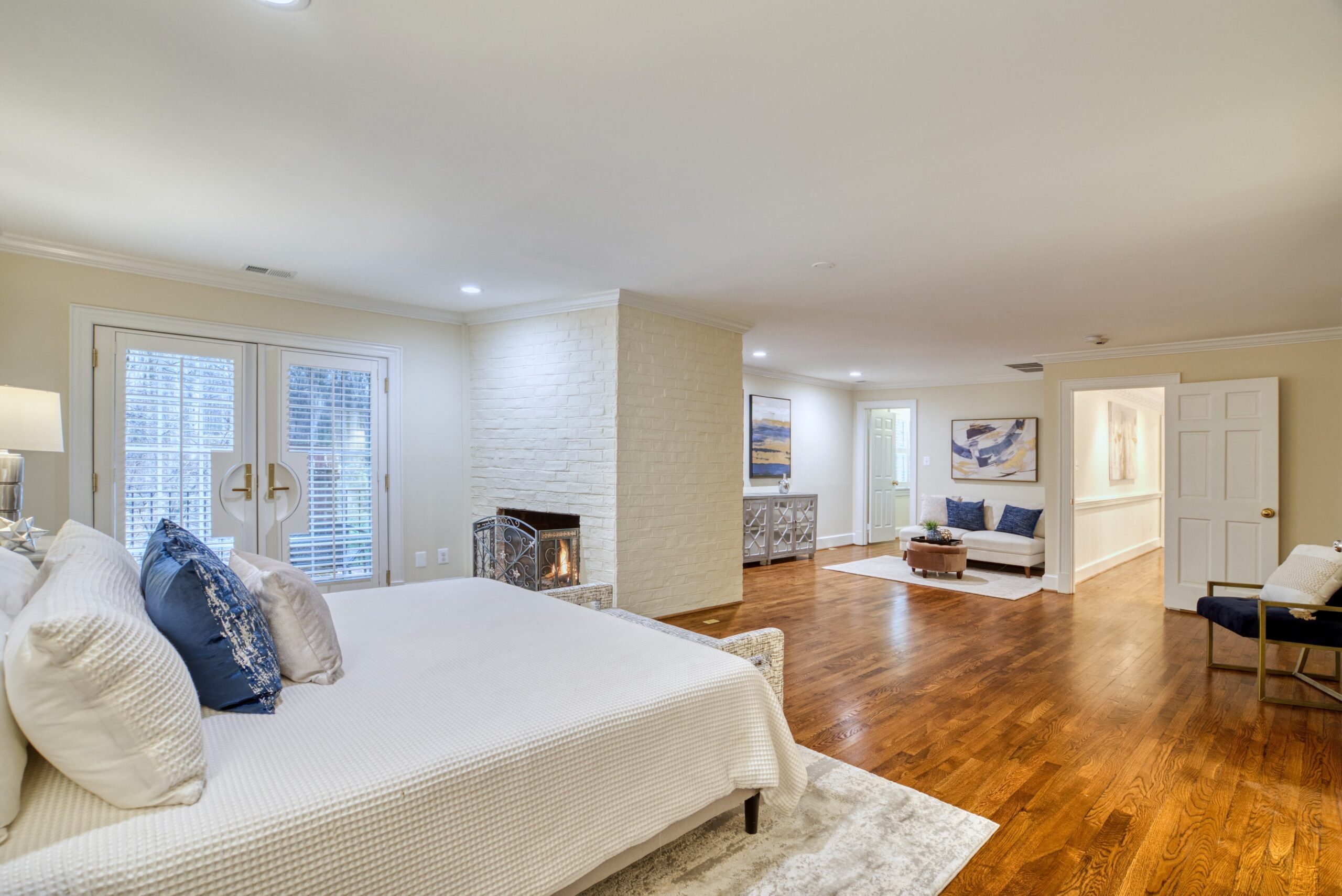 Professional interior photo of 718 Potomac Knolls Dr - showing the primary bedroom suite with white brick fireplace and sitting area and doors to private brick balcony