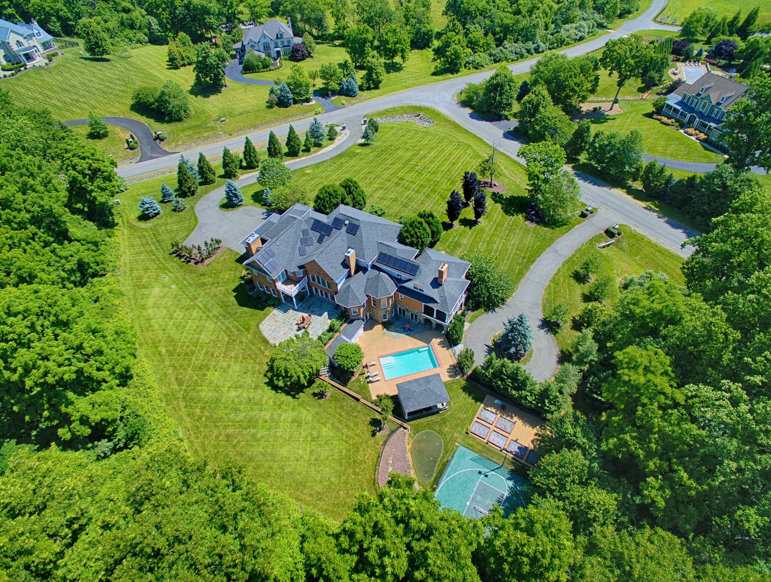 Exterior professional photo of 40573 Spectacular Bid Place - showing the whole property from a drone. Pool, basketball sport court, putting green and landscaping visible