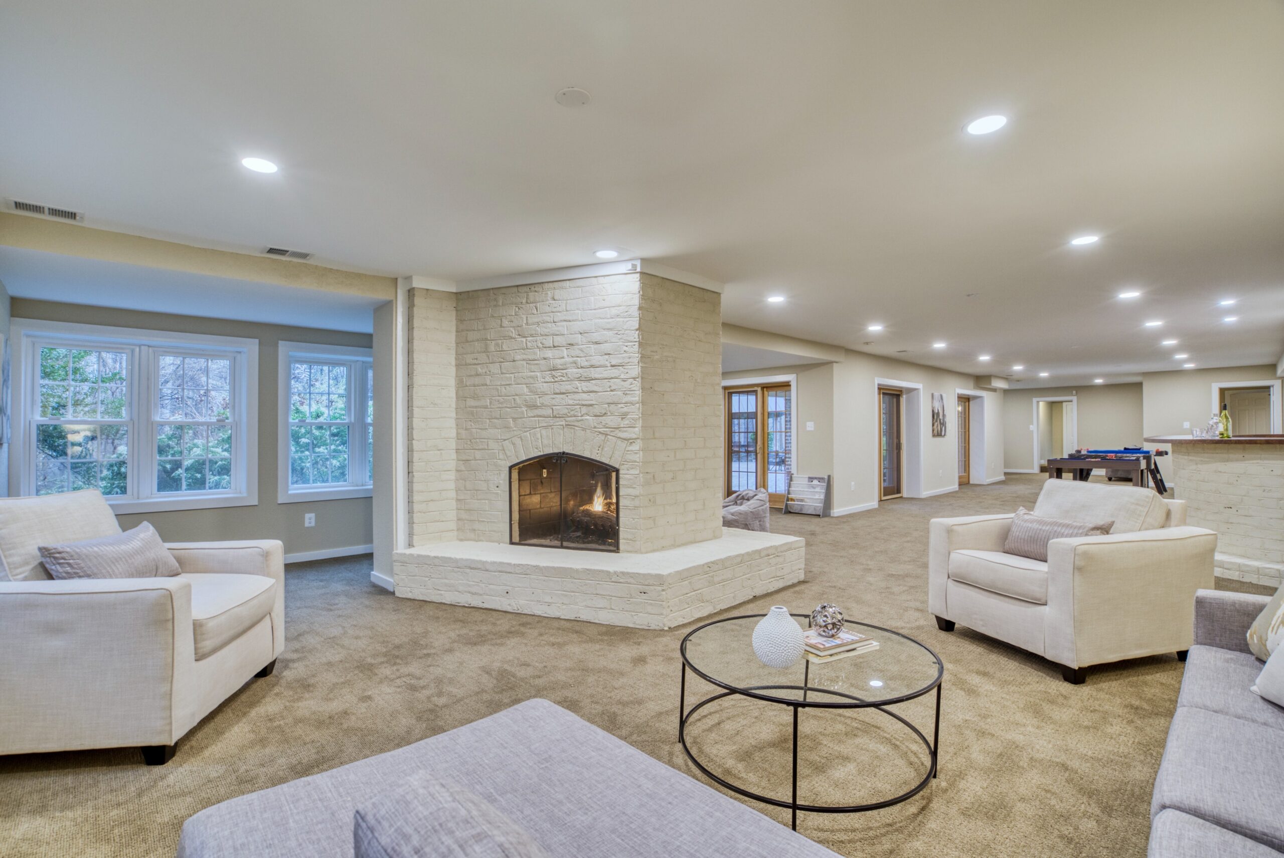 Professional interior photo of 718 Potomac Knolls Dr - showing the finished lower level with white brick double sided fireplace and several areas to sit/entertain