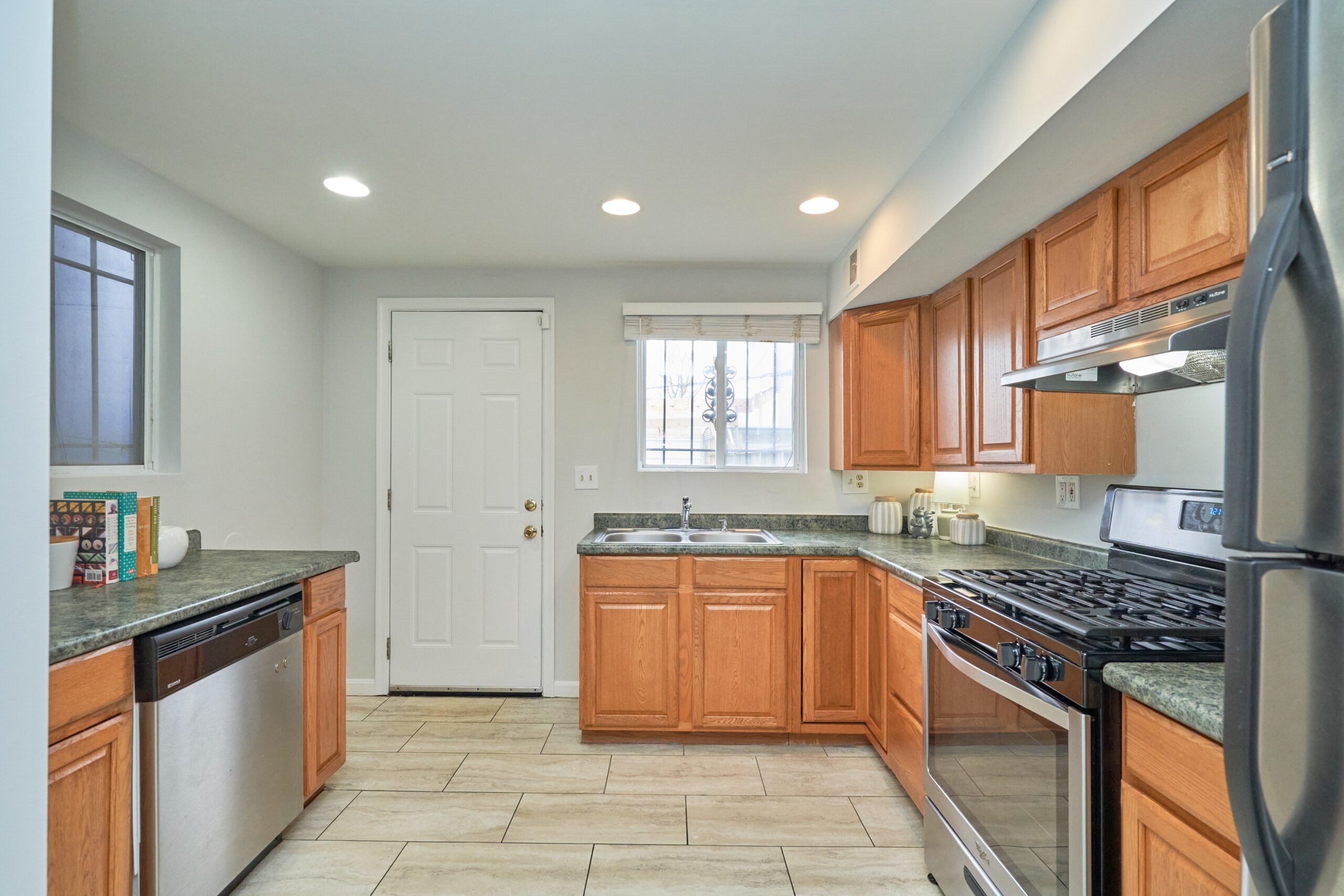 Professional interior photo of 1313 K Street SE, Washington, DC - showing the kitchen with walnut cabinets and stainless appliances and back door leading to the patio.