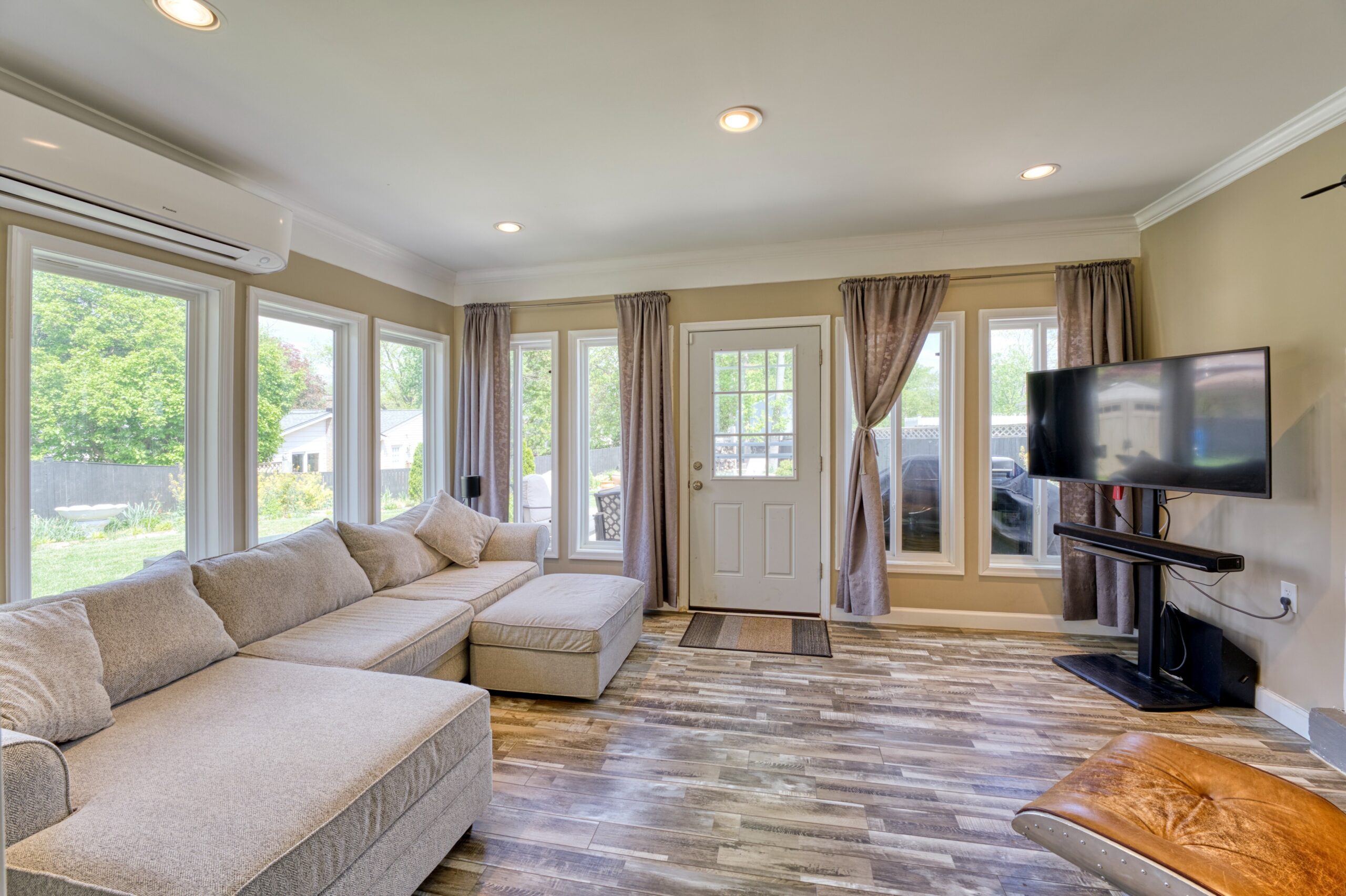 professional interior photo of 102 S Harrison Road, Sterling, VA - showing the rear living/sun room with LVP and a sectional couch facing a widescreen TV