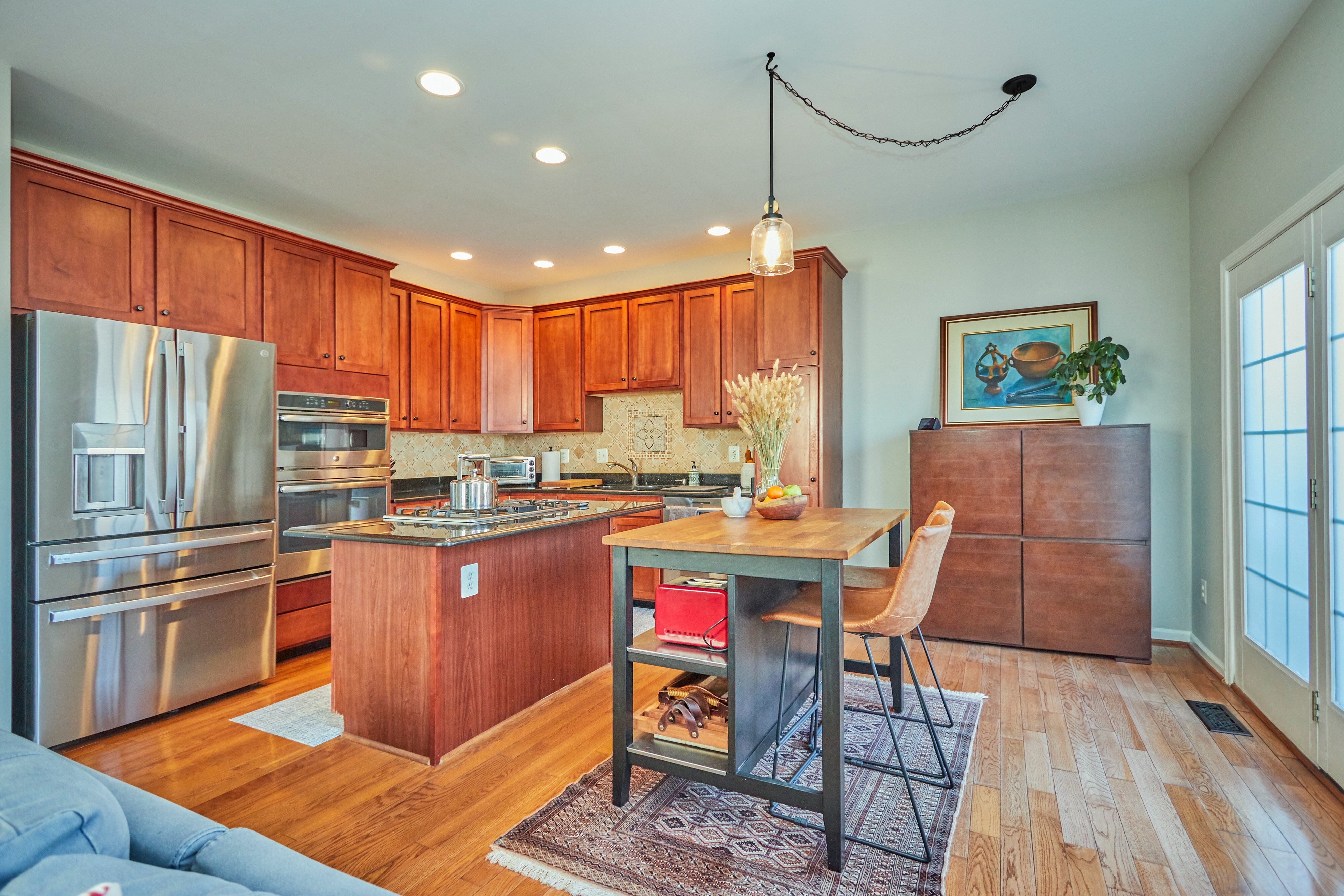 Professional interior photo of 25499 Beresford Drive, Chantilly, Virginia - showing the kitchen and breakfast area with stainless appliances and hardwood floors