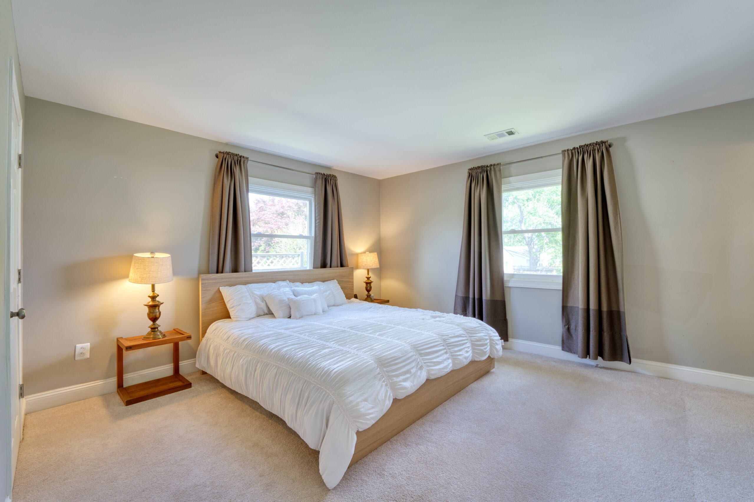 professional interior photo of 102 S Harrison Road, Sterling, VA - showing the primary bedroom with cream carpets, light gray walls and dark colorblock grey curtains