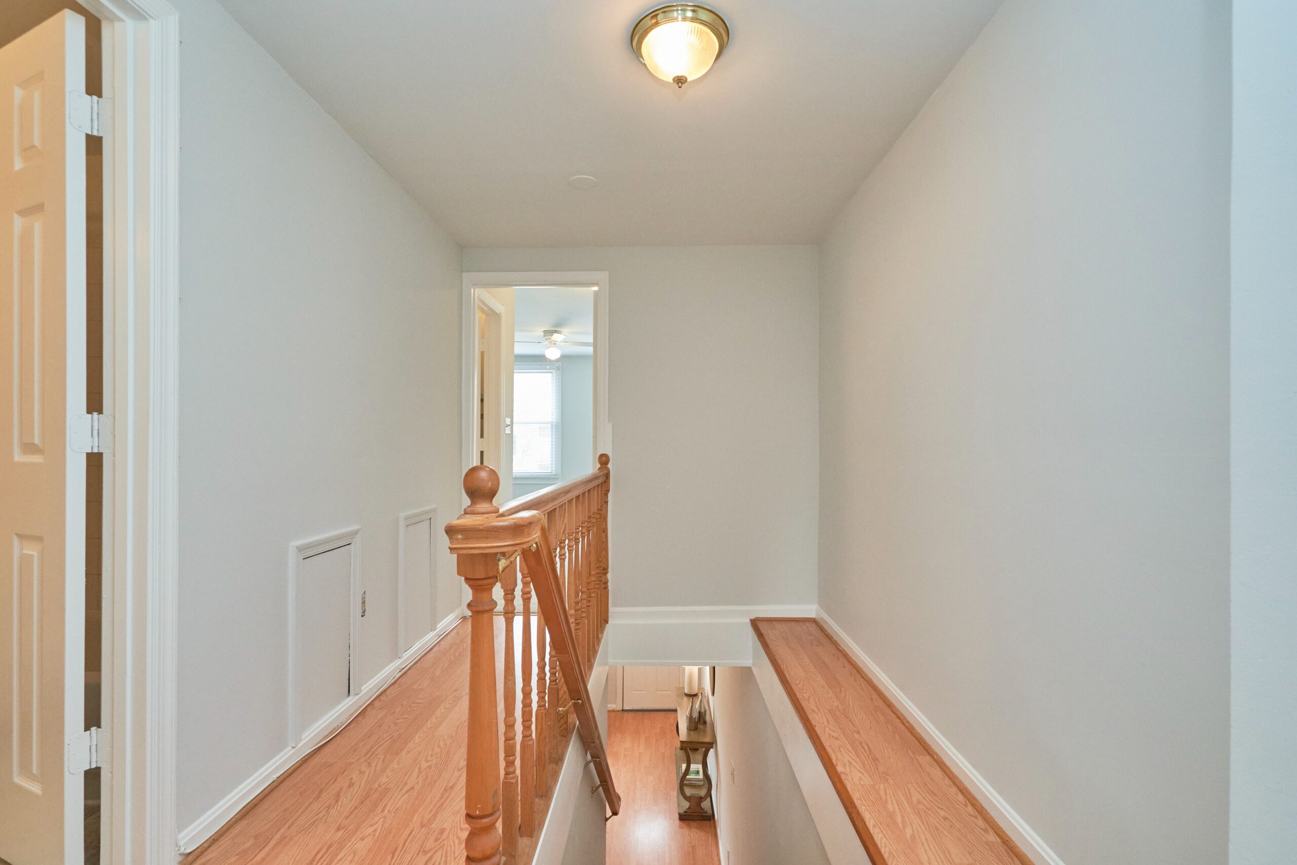 Professional interior photo of 1313 K Street SE, Washington, DC - showing the top of the stairs looking down to the main floor as well as down the narrow hallway to the bedroom