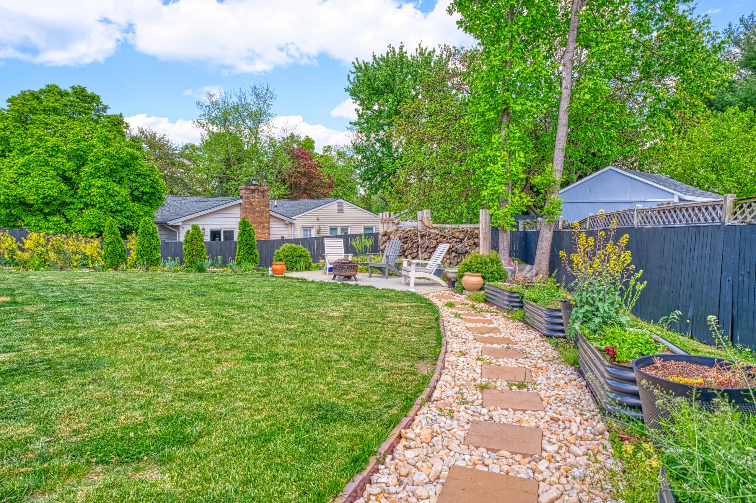 professional exterior photo of 102 S Harrison Road, Sterling, VA - showing the backyard pebble path leading to the separate patio with firepit