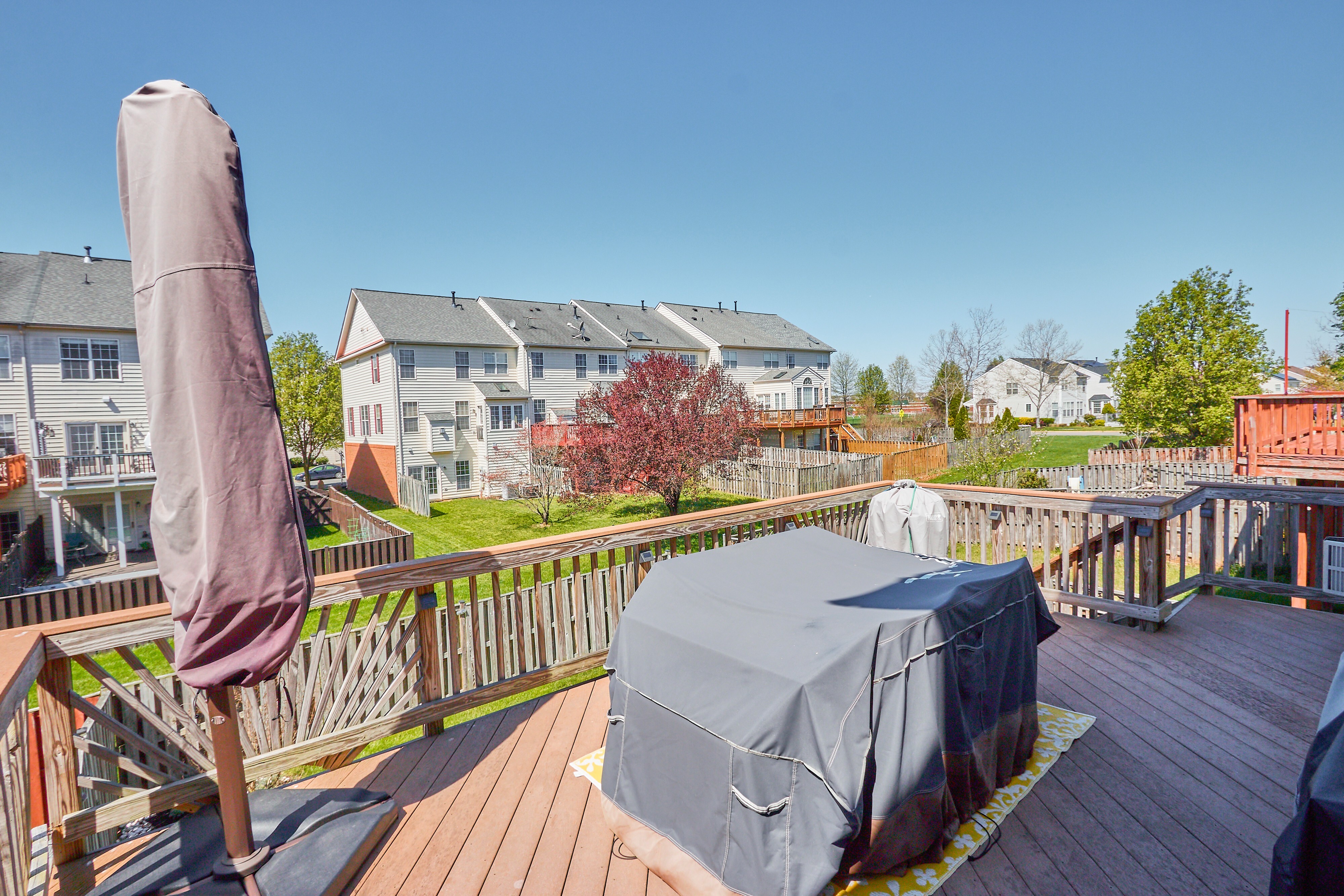 Professional exterior photo of 25499 Beresford Drive, Chantilly, Virginia - showing the deck and view behind the townhome
