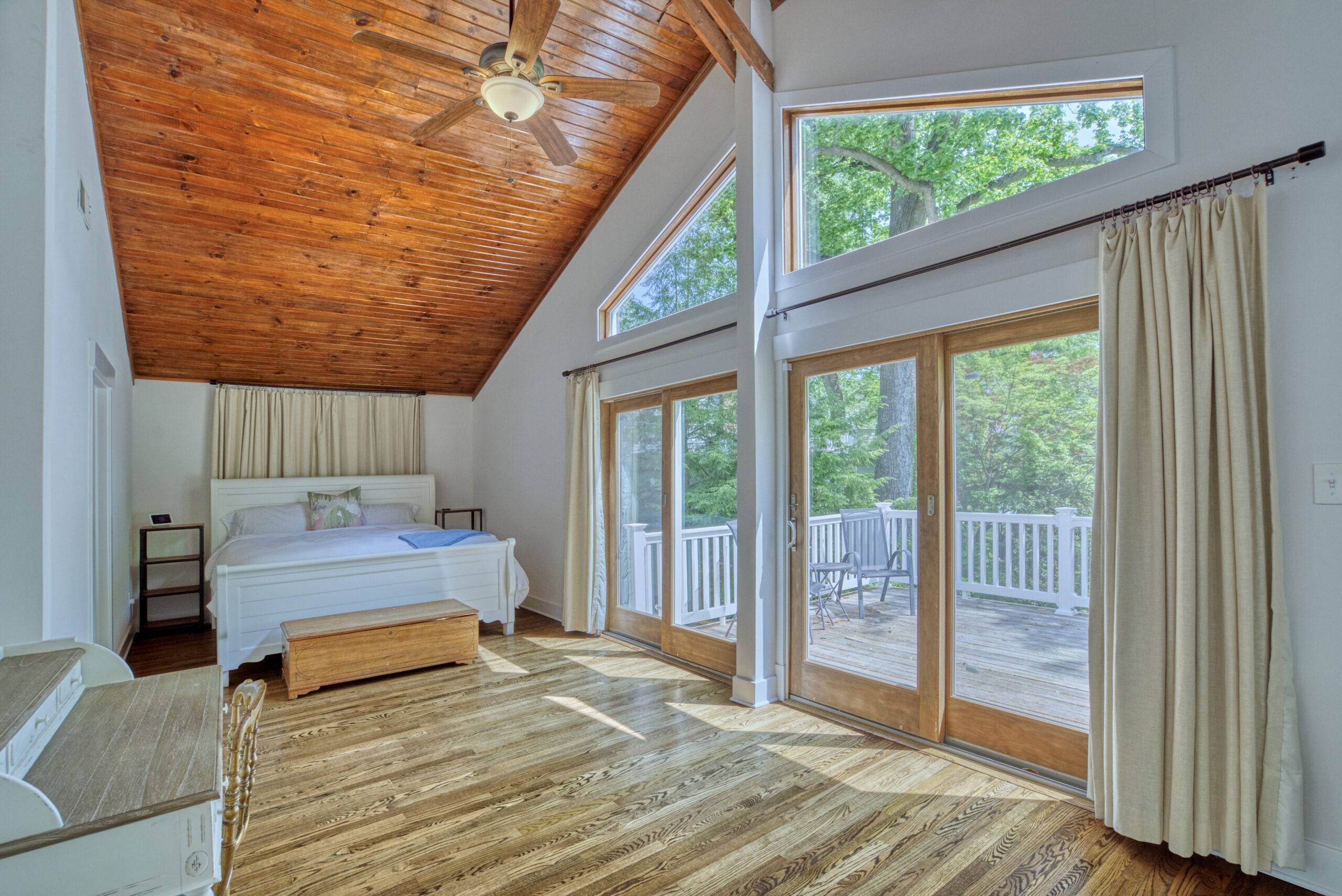 Professional interior photo of 209 Norwood Road, Annapolis, MD - showing the primary bedroom  with the bed next to 2 sliding double doors to the private balcony with vaulted hardwood ceiling