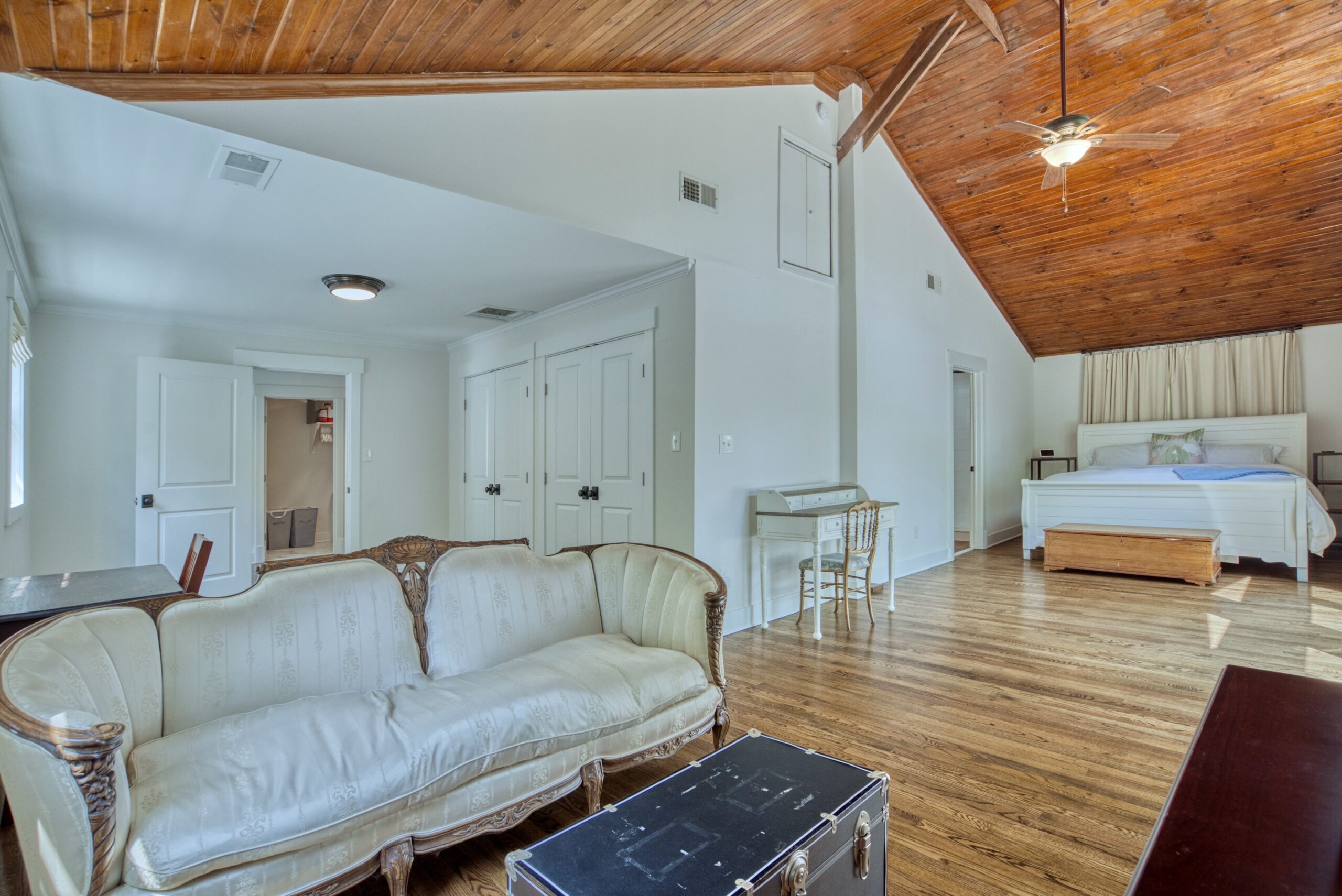 Professional interior photo of 209 Norwood Road, Annapolis, MD - showing the sitting area of the primary suite with the bed space in the back and vaulted hardwood ceiling