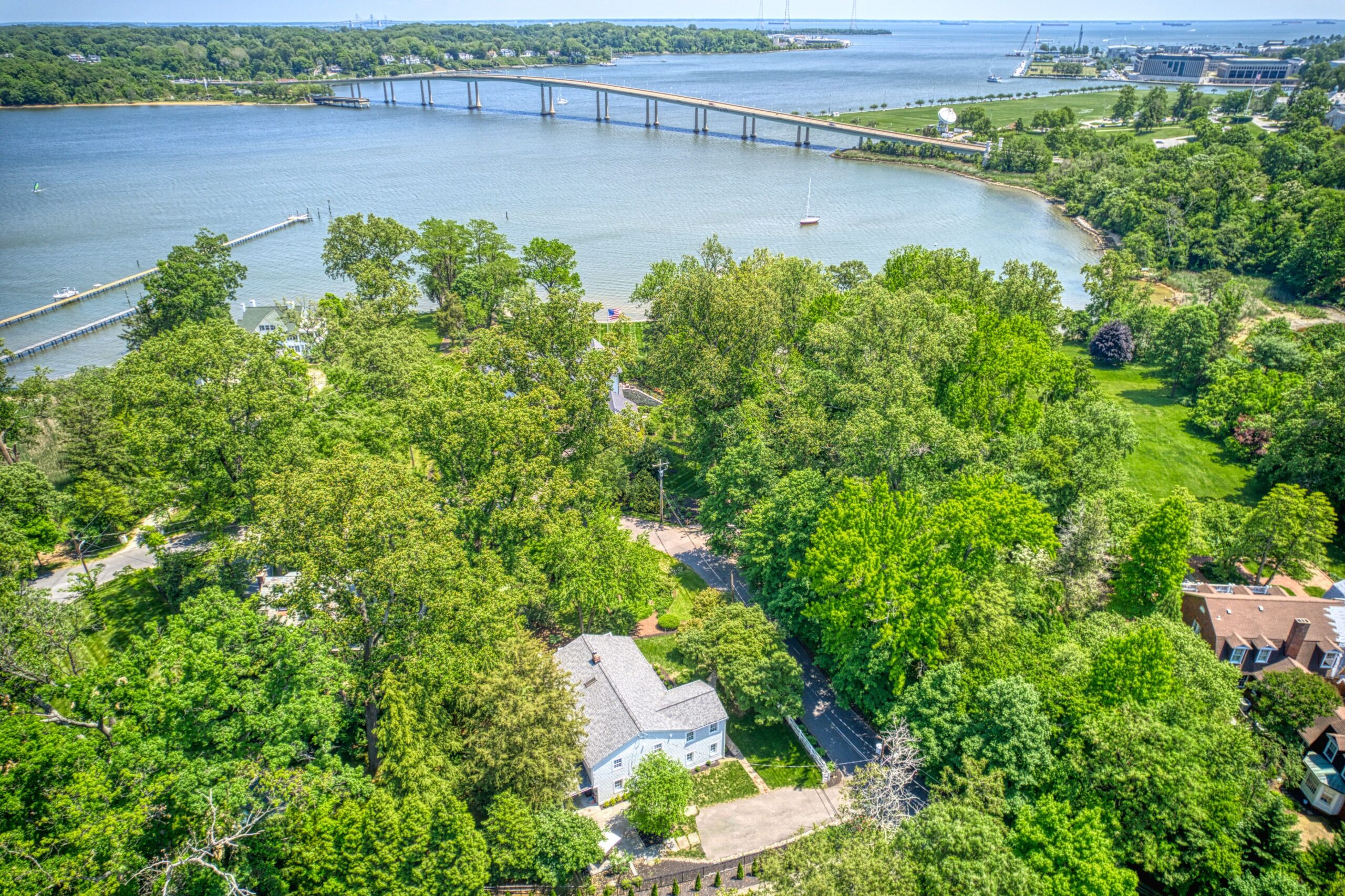 Professional aerial exterior photo of 209 Norwood Road, Annapolis, MD - showing the home in the foreground and the Severn River in the background, visible to thehome