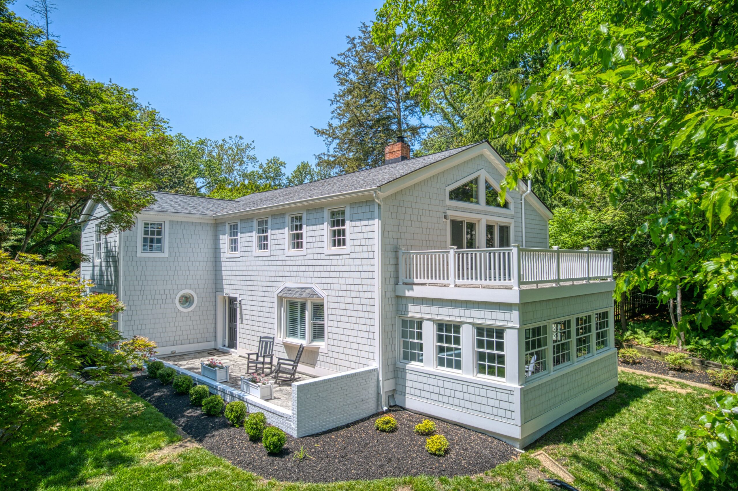 Professional aerial exterior photo of 209 Norwood Road, Annapolis, MD - showing the front corner of the home with main level patio and sunroom visible surrounded by trees