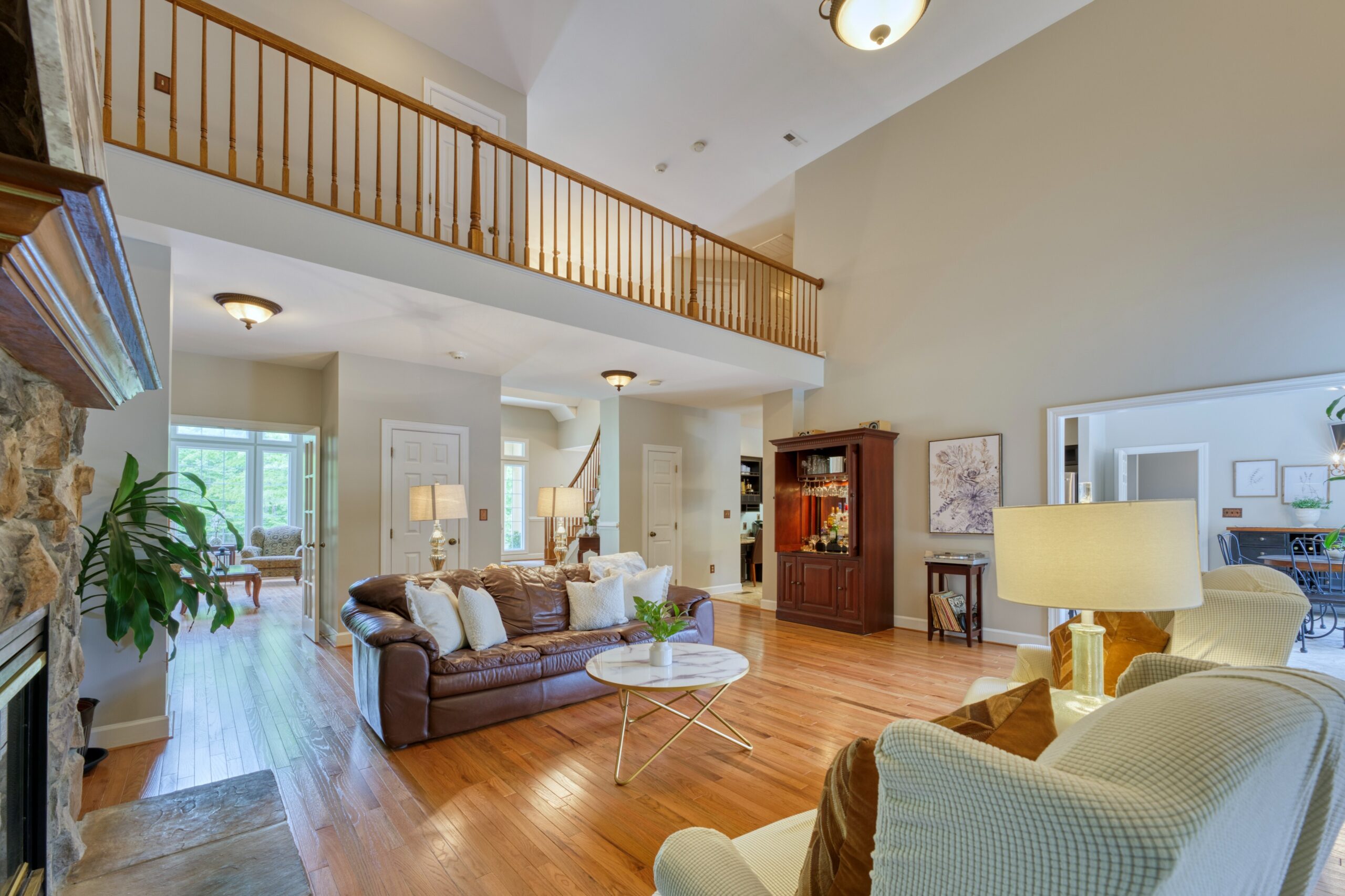 Professional interior photo of 13700 Holly Forest Dr - showing the main living room with hardwood floors, looking away from the windows at the 2nd floor catwalk
