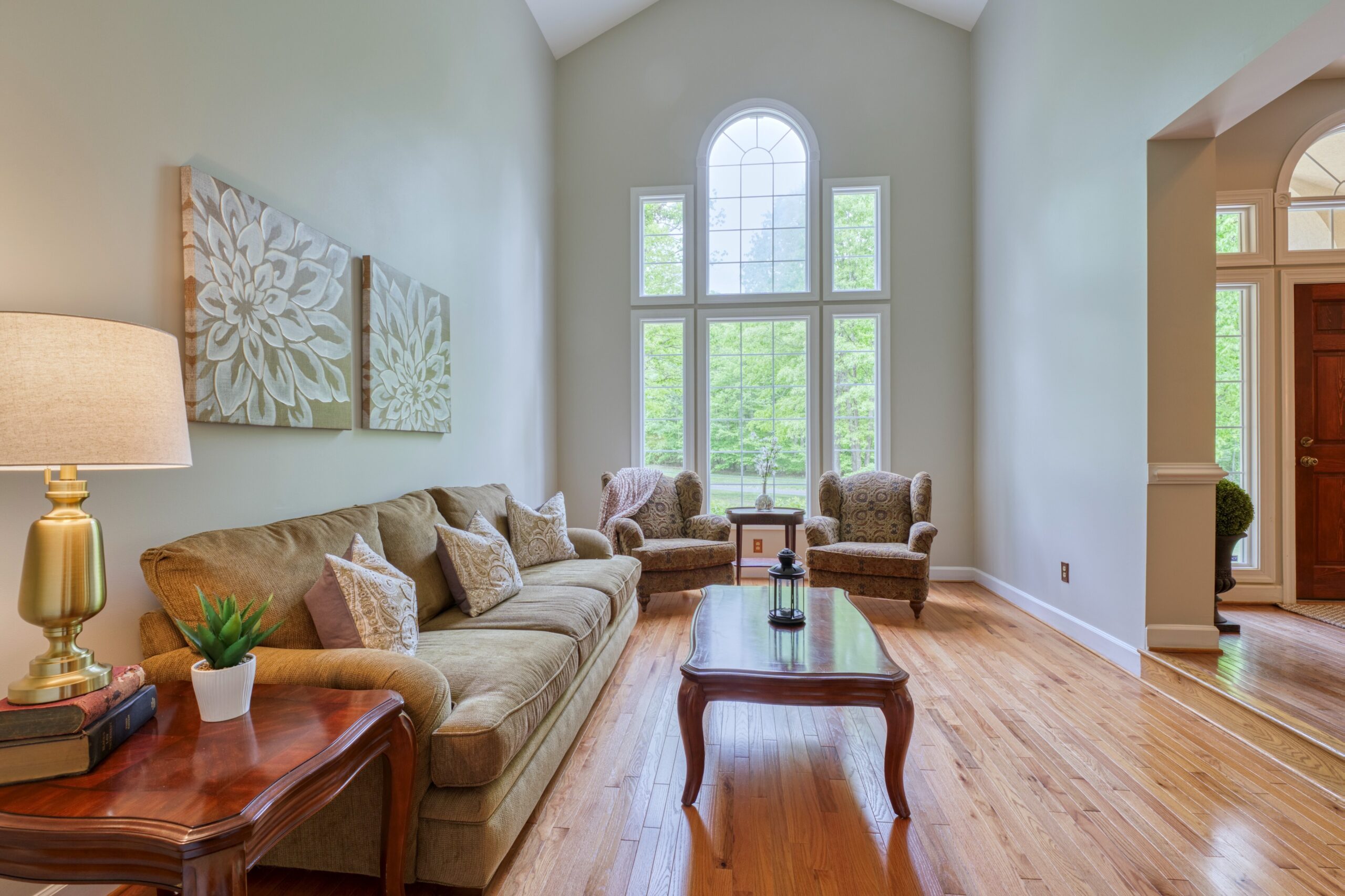 Professional interior photo of 13700 Holly Forest Dr - showing the formal living room with 1.5 story arched windows and hardwood floors