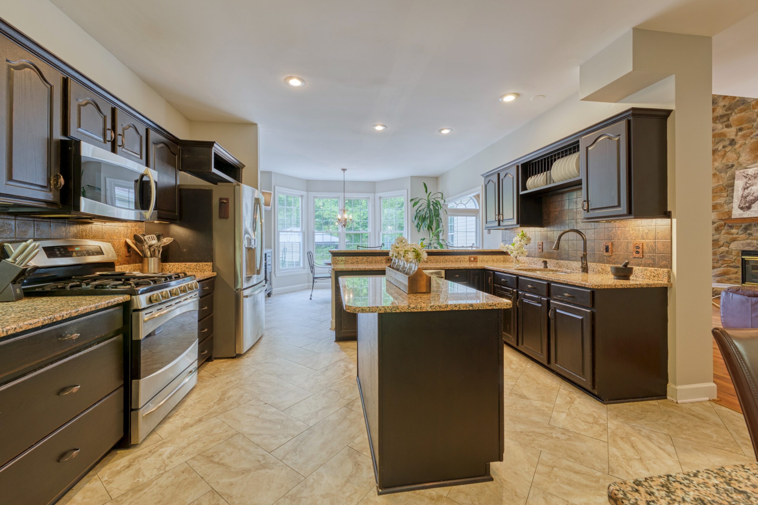 Professional interior photo of 13700 Holly Forest Dr - showing the kitchen with dark wood cabinets and cream colored granite and an island