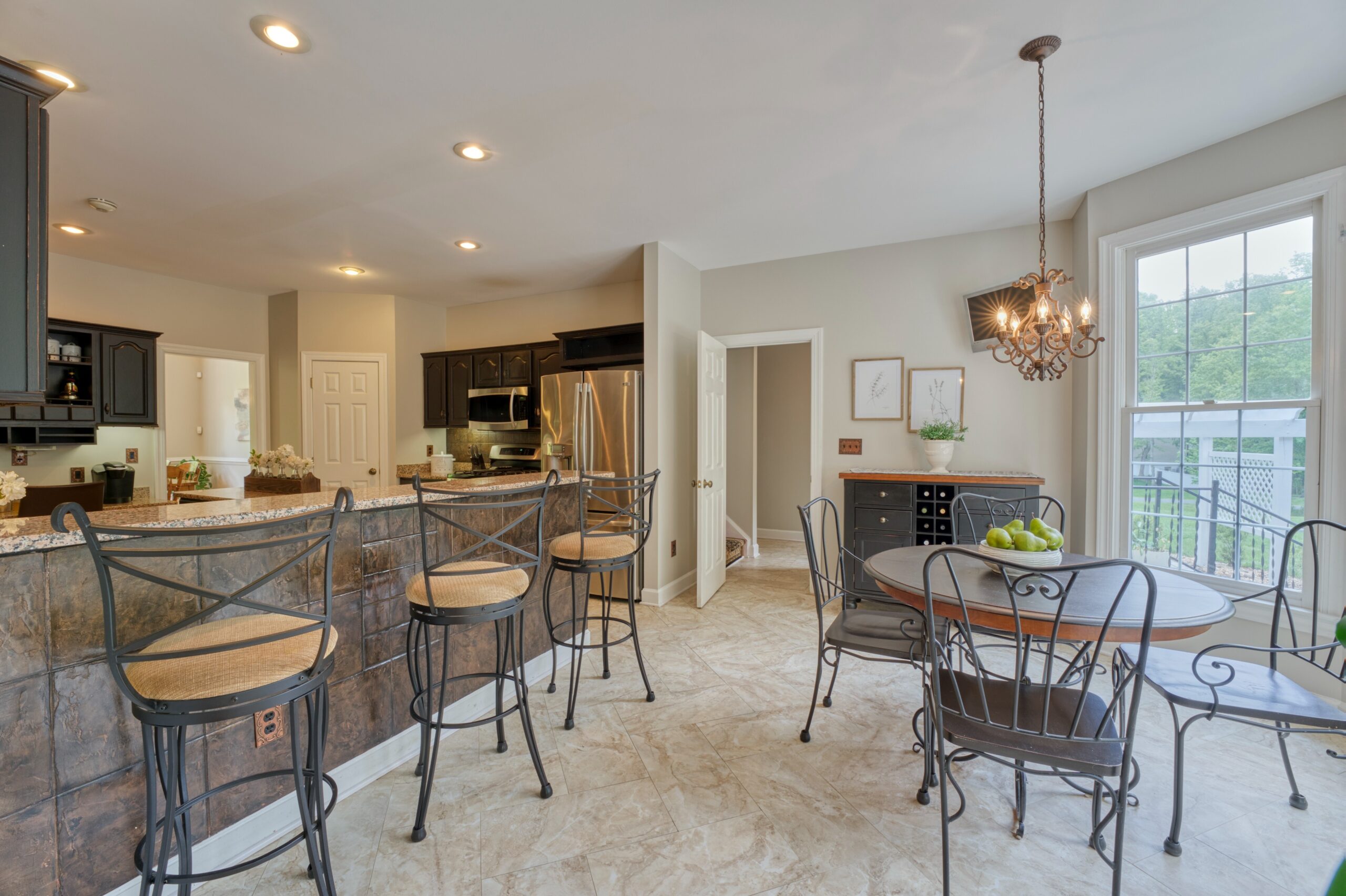 Professional interior photo of 13700 Holly Forest Dr - showing the breakfast area adjacent to the kitchen as well as the kitchen counter bar and 3 barstools