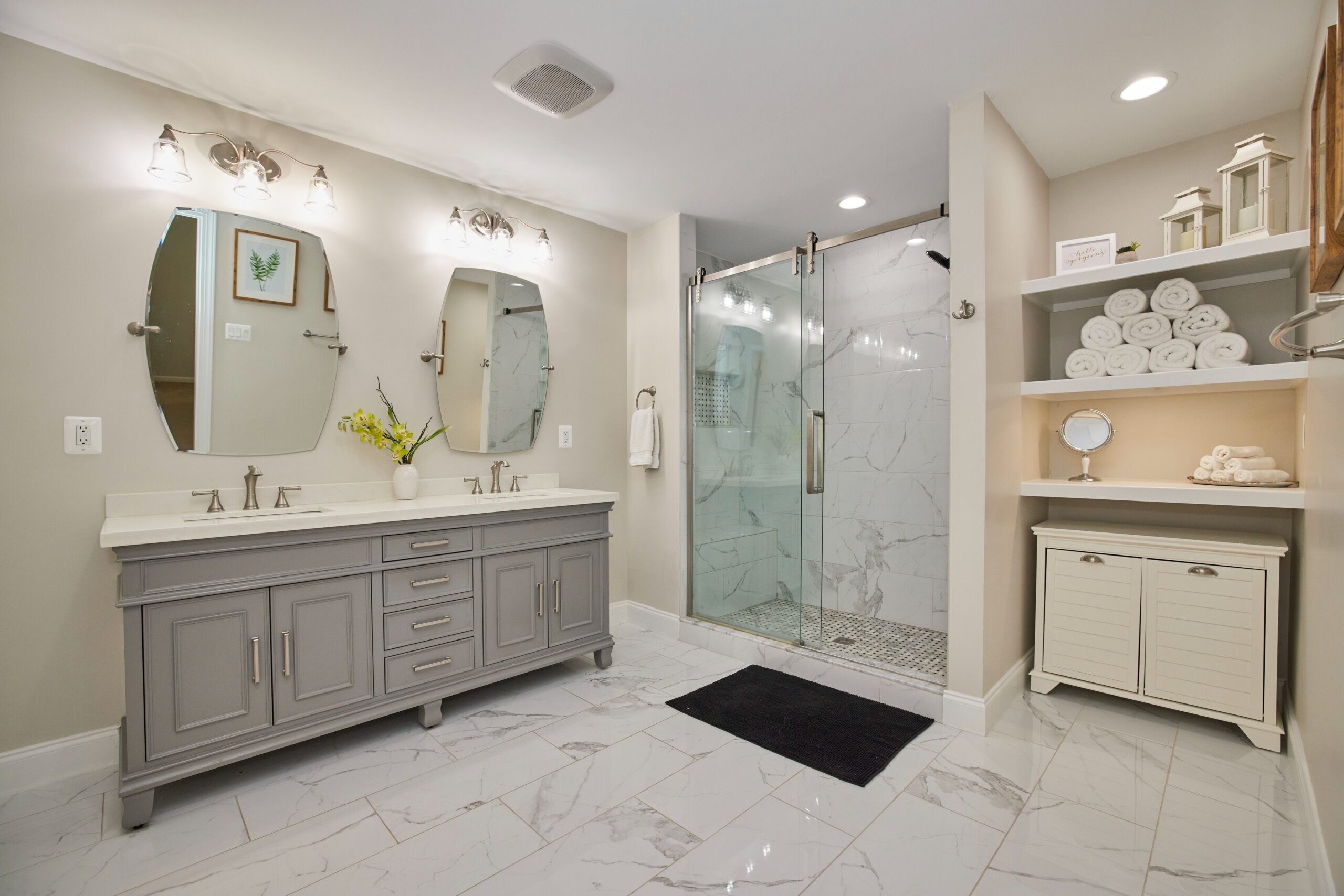 Professional interior photo of 12030 Lake Dorian Drive, Bristow, VA - showing the primary bathroom with dual vanity, large zero-entry shower and open linen shelves and white quartz tile floors