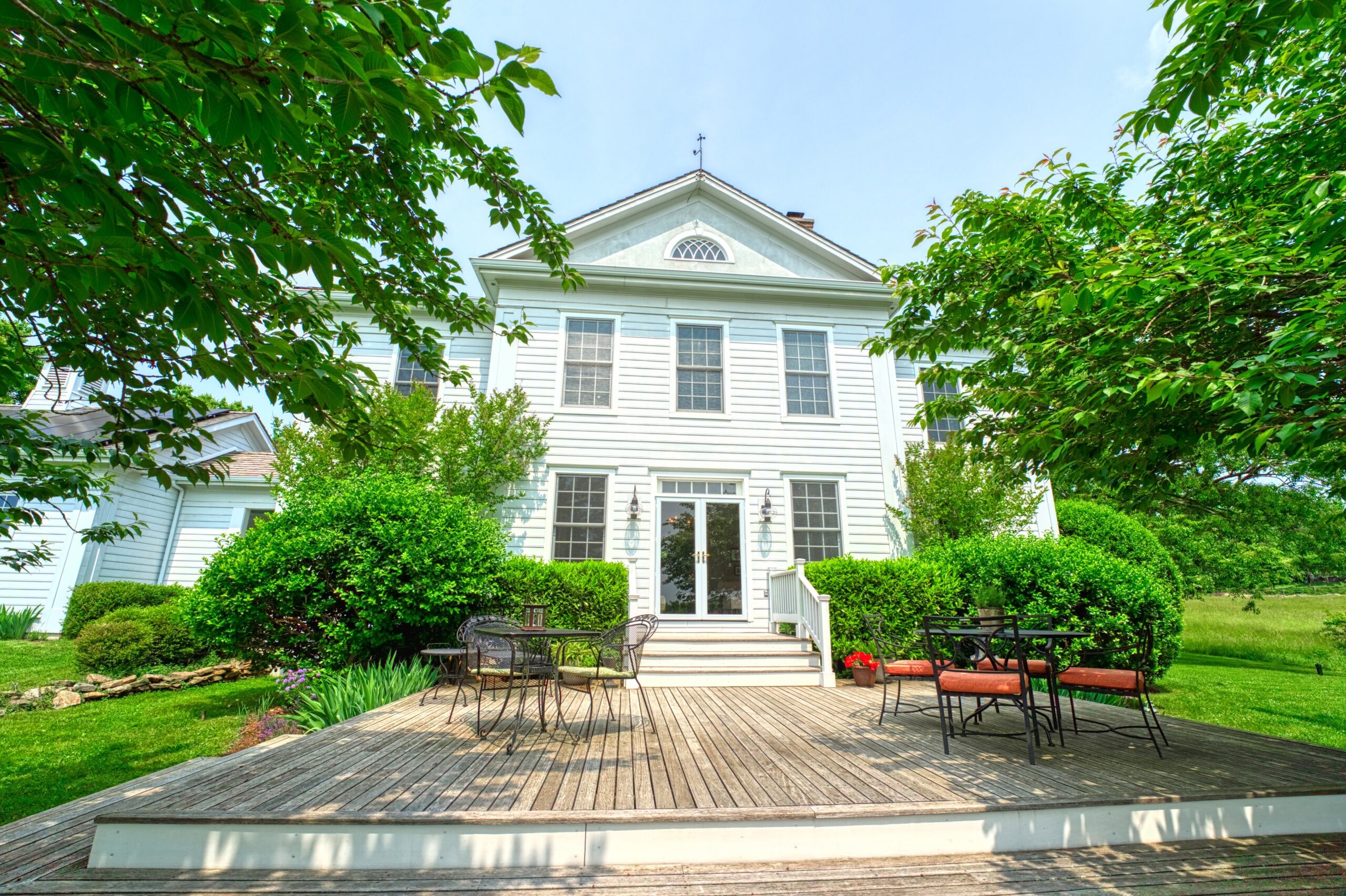 Professional exterior photo of 15203 Clover Hill Road - showing the rear deck from ground level looking back toward the white house