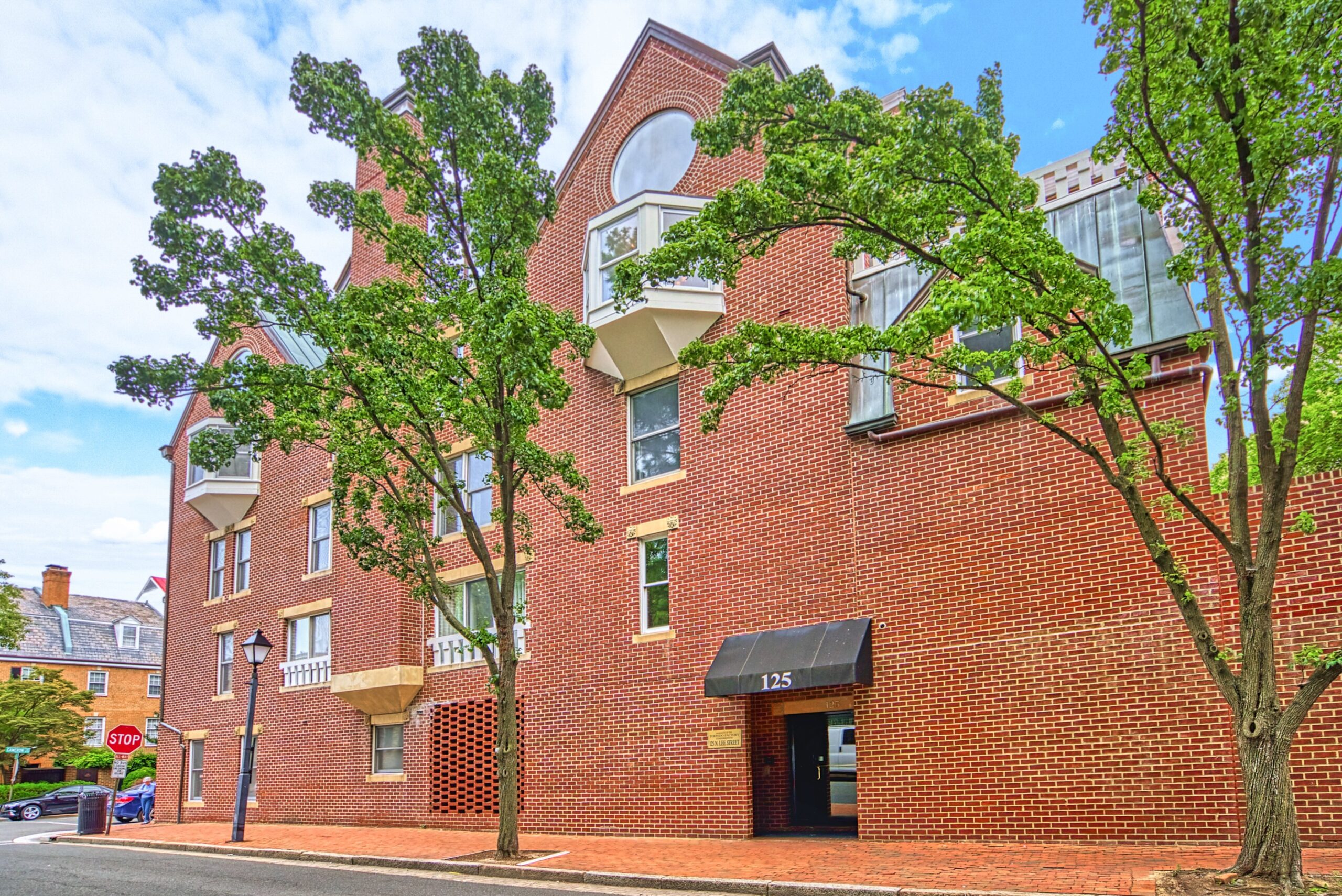 Professional exterior photo of 125 N Lee St, Alexandria, VA - showing the entry vestibule and brick side of the building and sidewalk