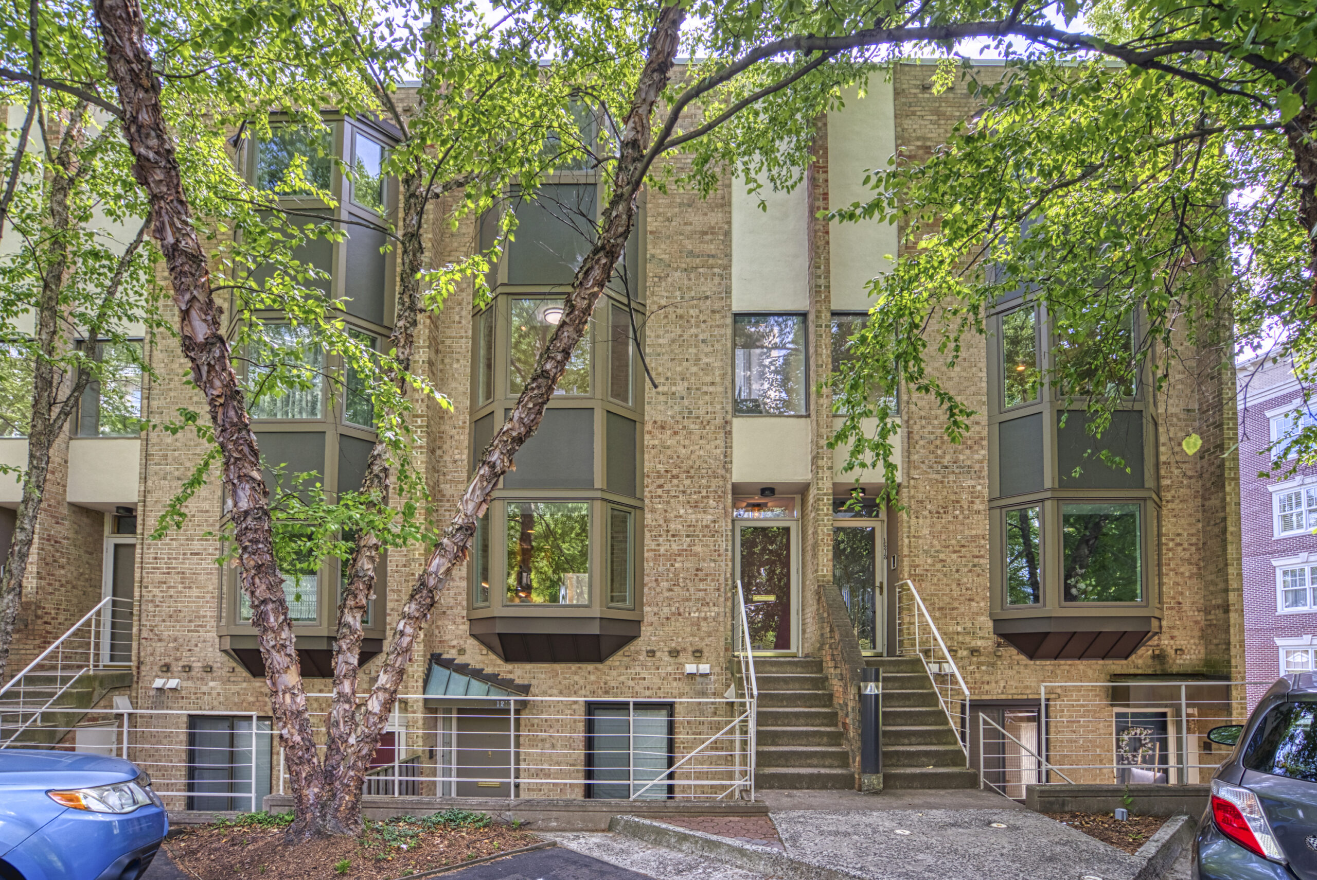 Professional exterior photo of 1215 N Nash St #1, Arlington - showing the street view of a brick brownstone townhome-style condo with stairs leading up to the first floor entrance and down to a ground floor storage unit