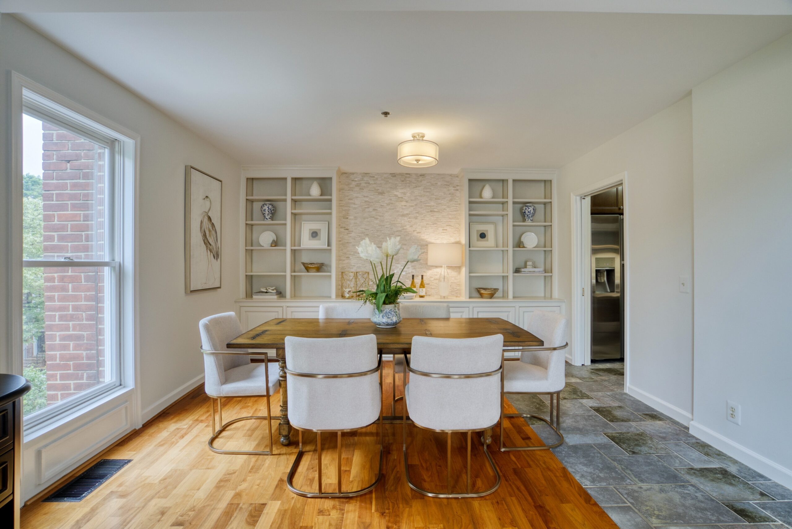 Professional interior photo of 125 N Lee St #401, Alexandria, VA - showing the dining room with built-in shelves, stone statement wall, hardwood and stone tile floors