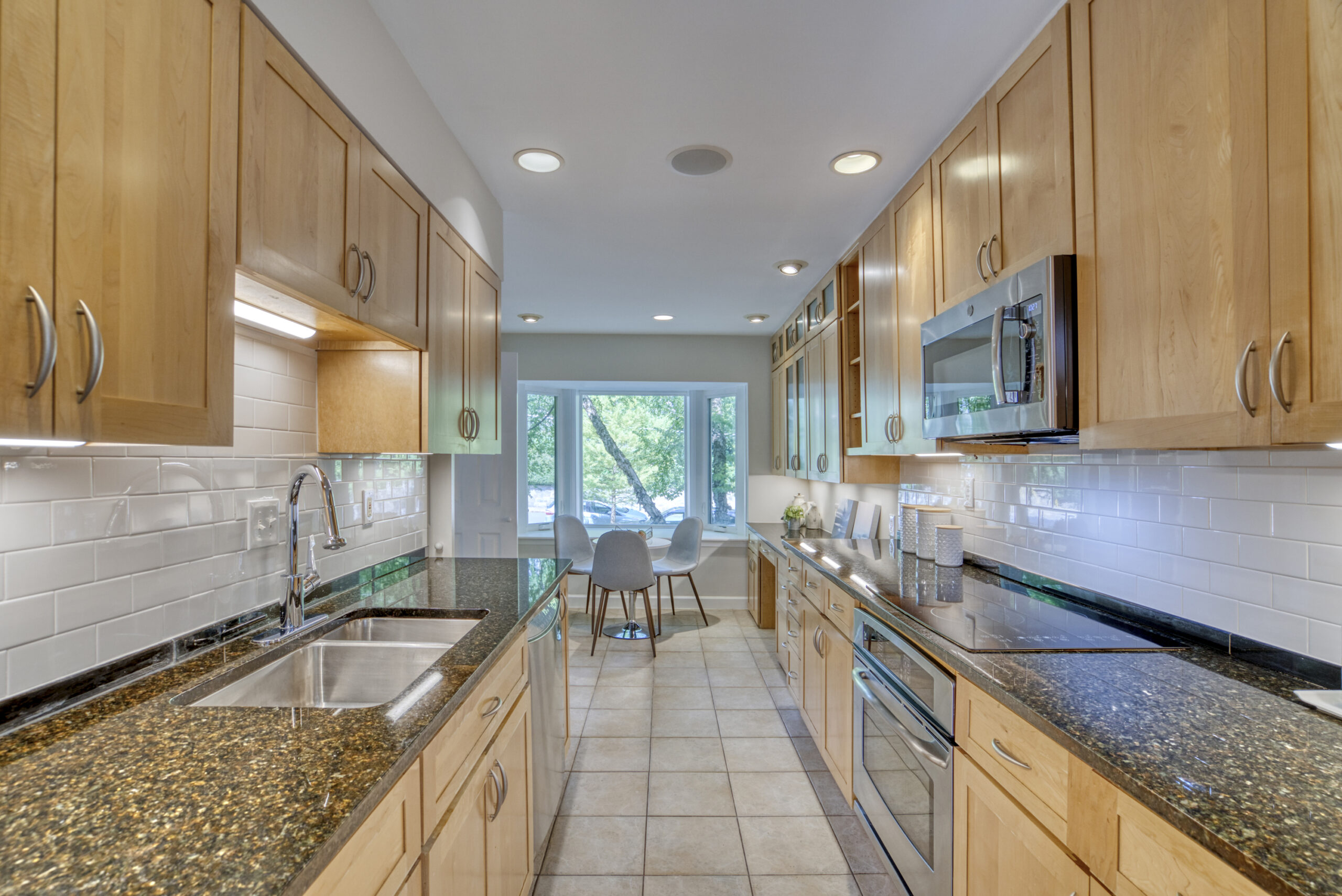 Professional interior photo of 1215 N Nash St #1, Arlington - showing the galley kitchen looking from the back towards the front of the home with bay windows and kitchen table in the background