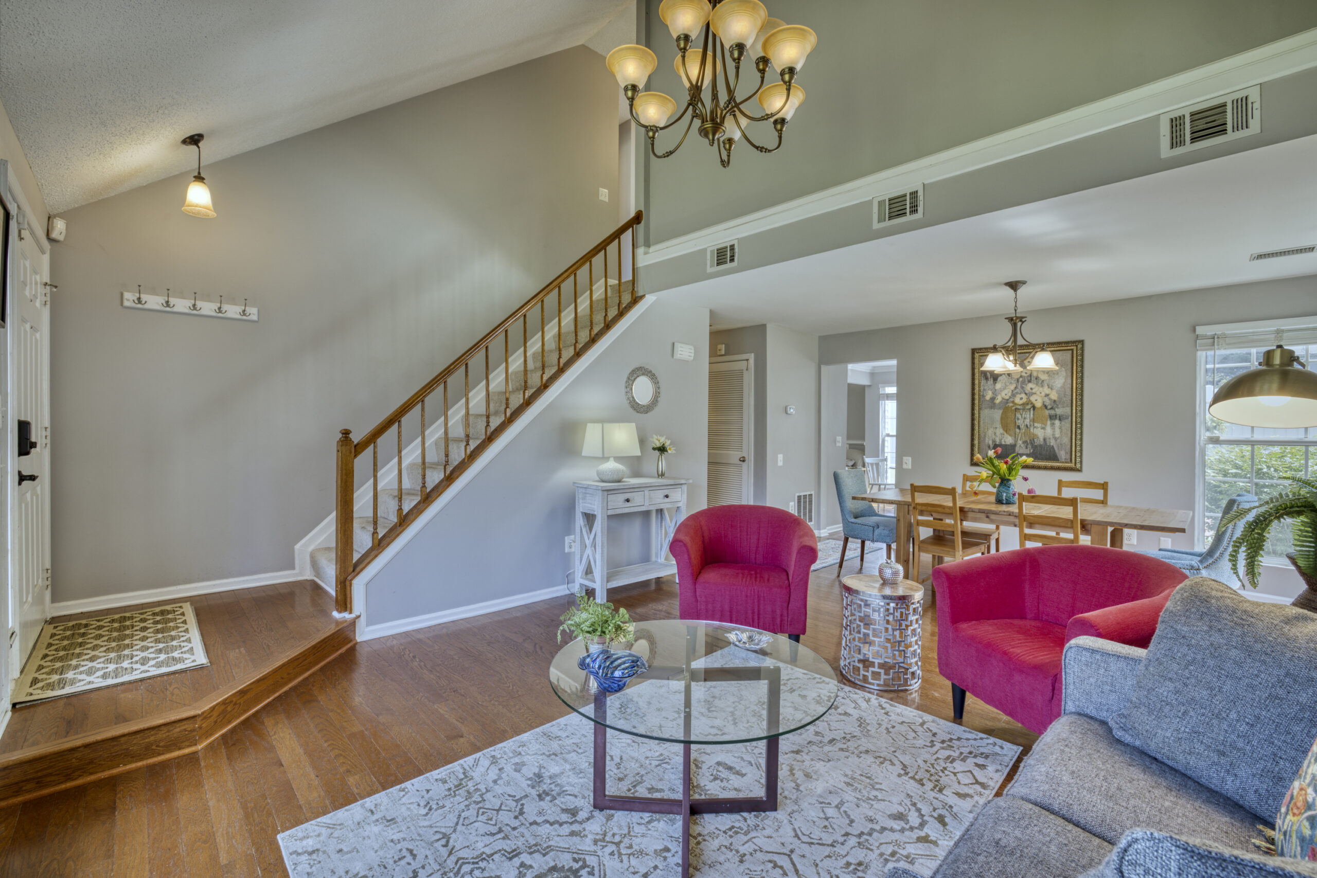Professional interior photo of 12309 Stalwart Court - showing the front living room with vaulted ceiling, hardwood floors, stairs to the second floor and open dining room in the background