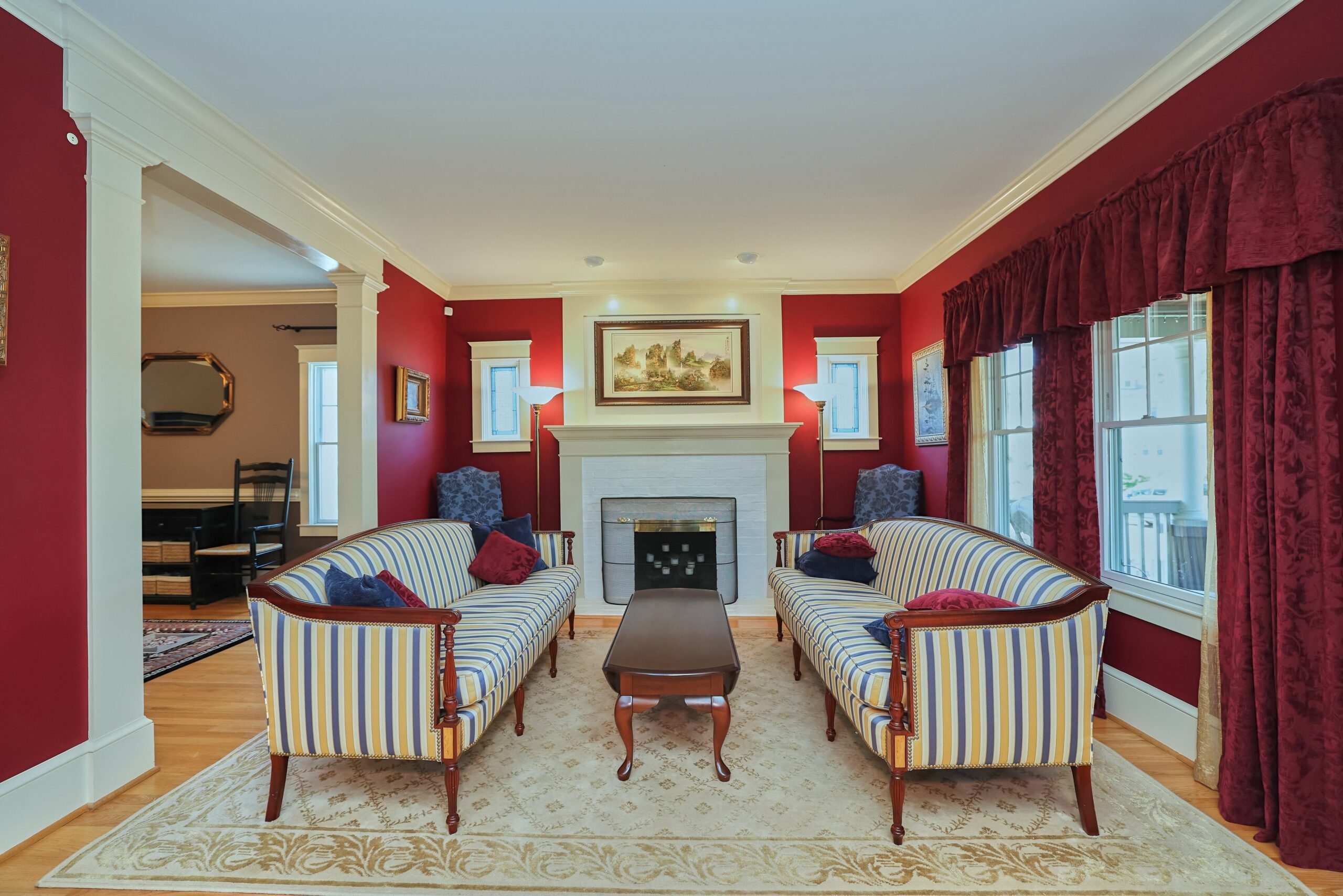 Professional interior photo of 819 N Fillmore St - Showing the front formal sitting room with red jewel-toned walls, curtains and throw pillows looking directly at a wood fireplace