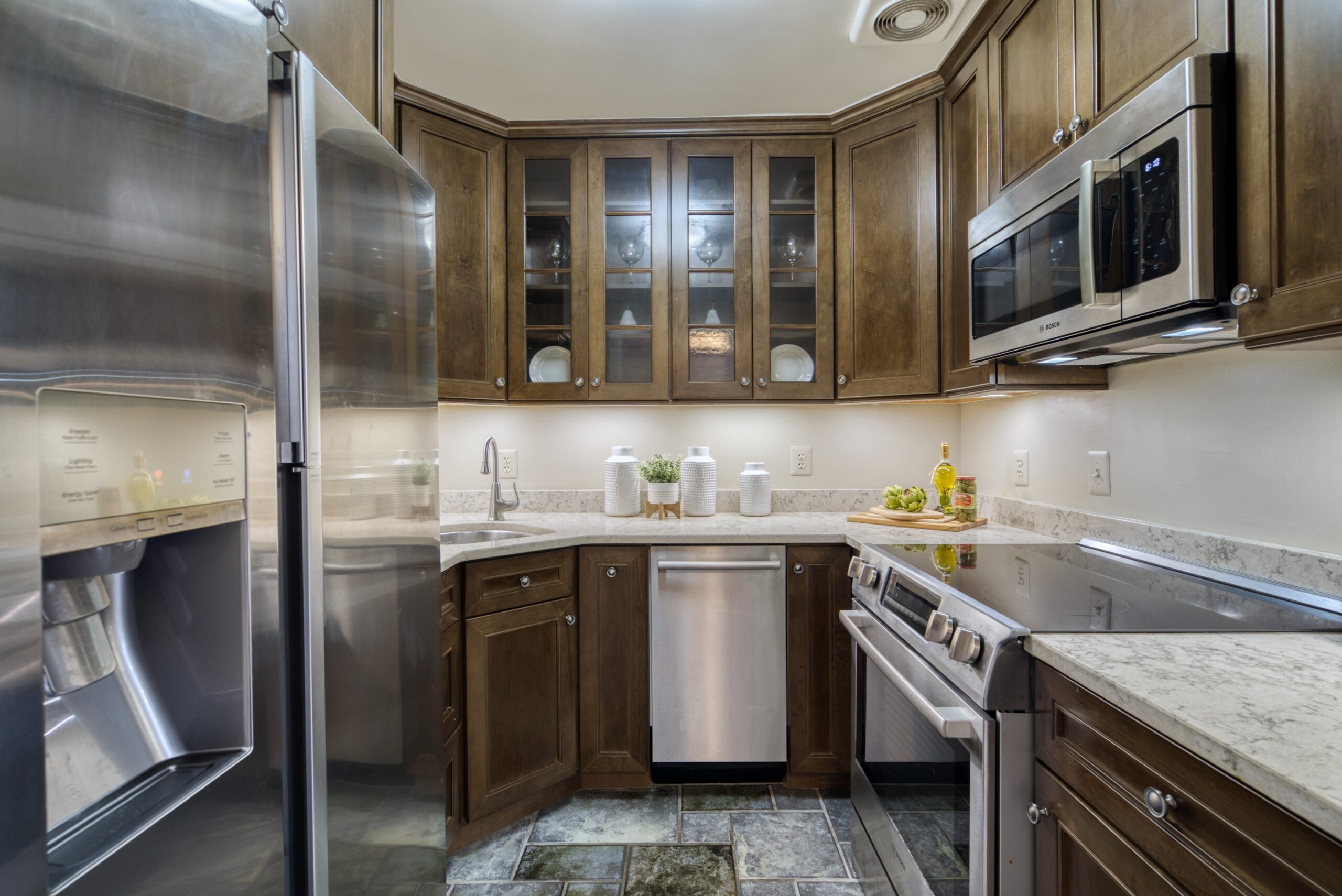 Professional interior photo of 125 N Lee St #401, Alexandria, VA - showing the kitchen with dark wood cabinets, stainless appliances, and granite counters