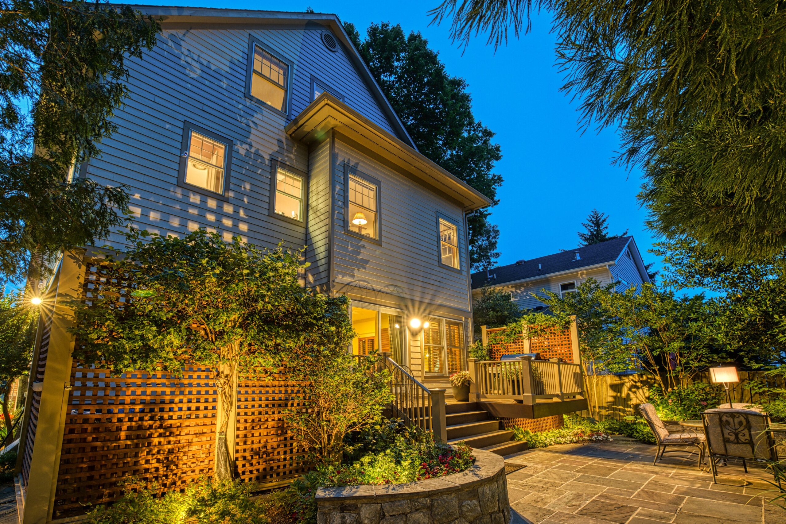 Professional exterior photo taken at dusk of 819 N Fillmore St - Showing the rear of the home looking back at the raised deck and along the flagstone patio