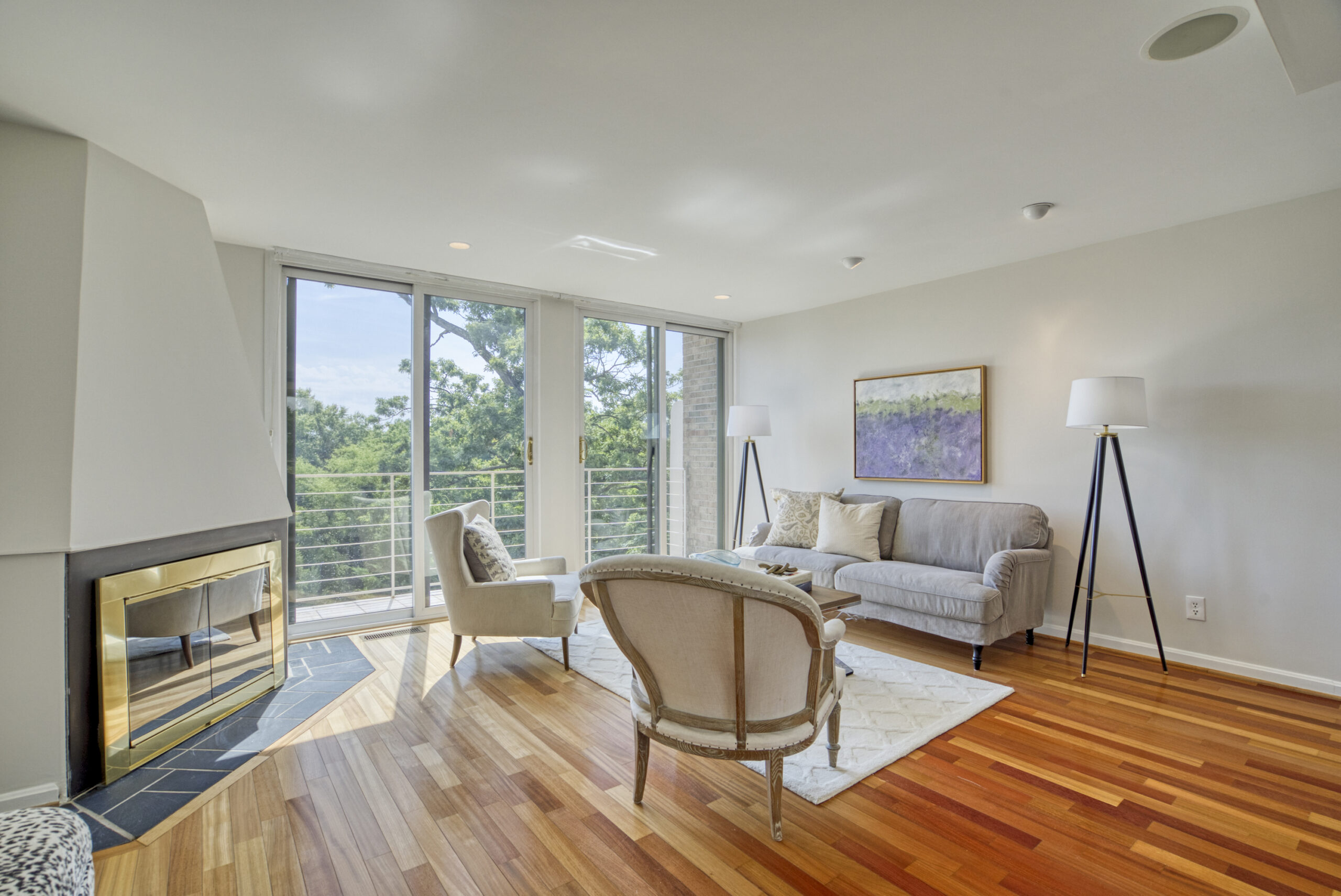 Professional interior photo of 1215 N Nash St #1, Arlington - showing the living room from the perspective of standing at the wet bar with hardwood floors, built-in fireplace and large glass balcony doors