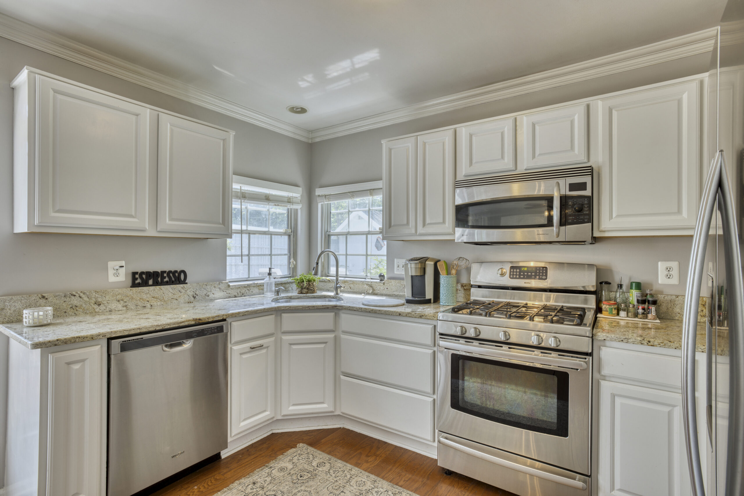 Professional interior photo of 12309 Stalwart Court - showing the kitchen with white cabinets, cream granite counters and stainless appliances