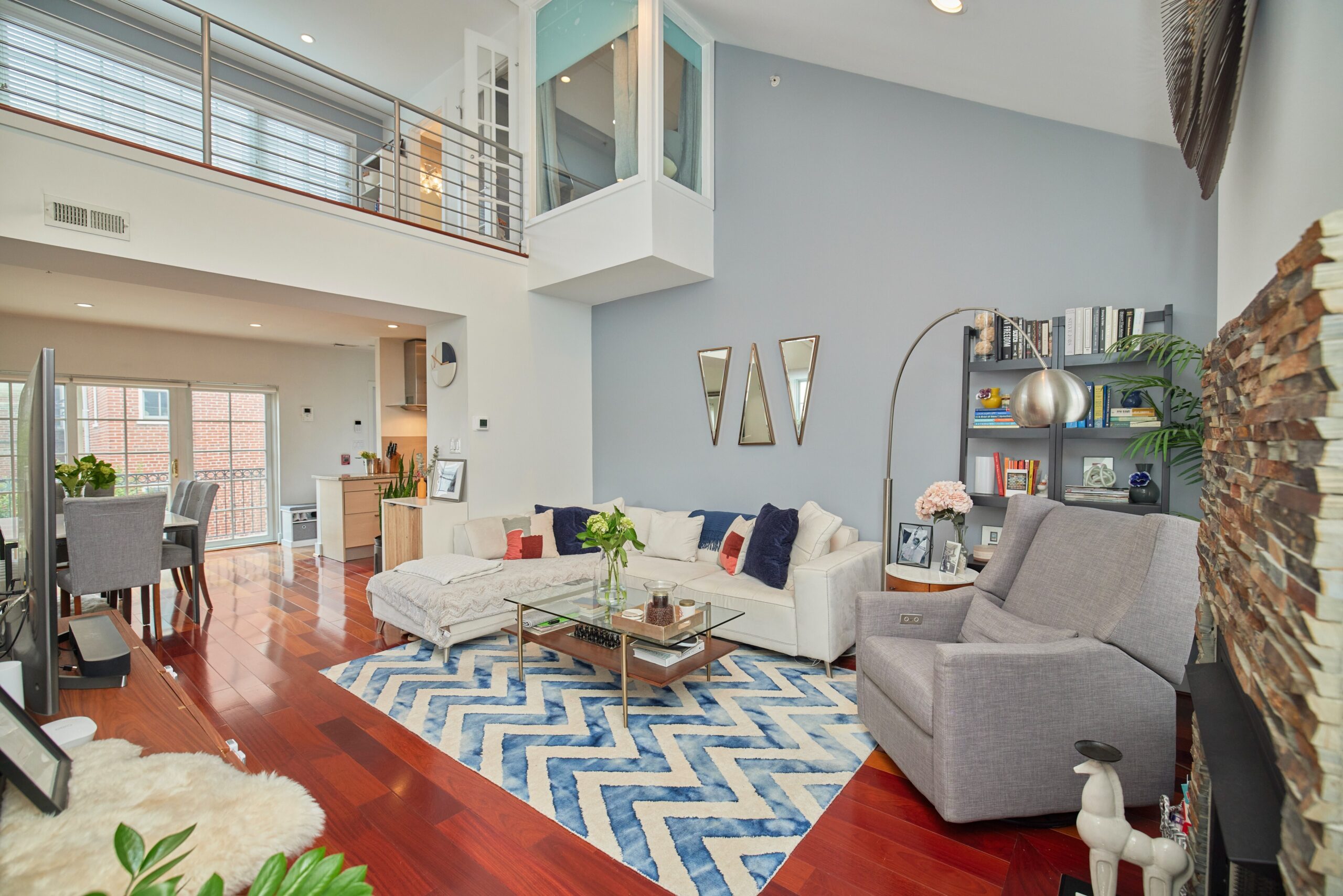 Professional interior photo of 1459 Harvard St NW #6 - showing the living room looking up toward the loft and loft bedroom