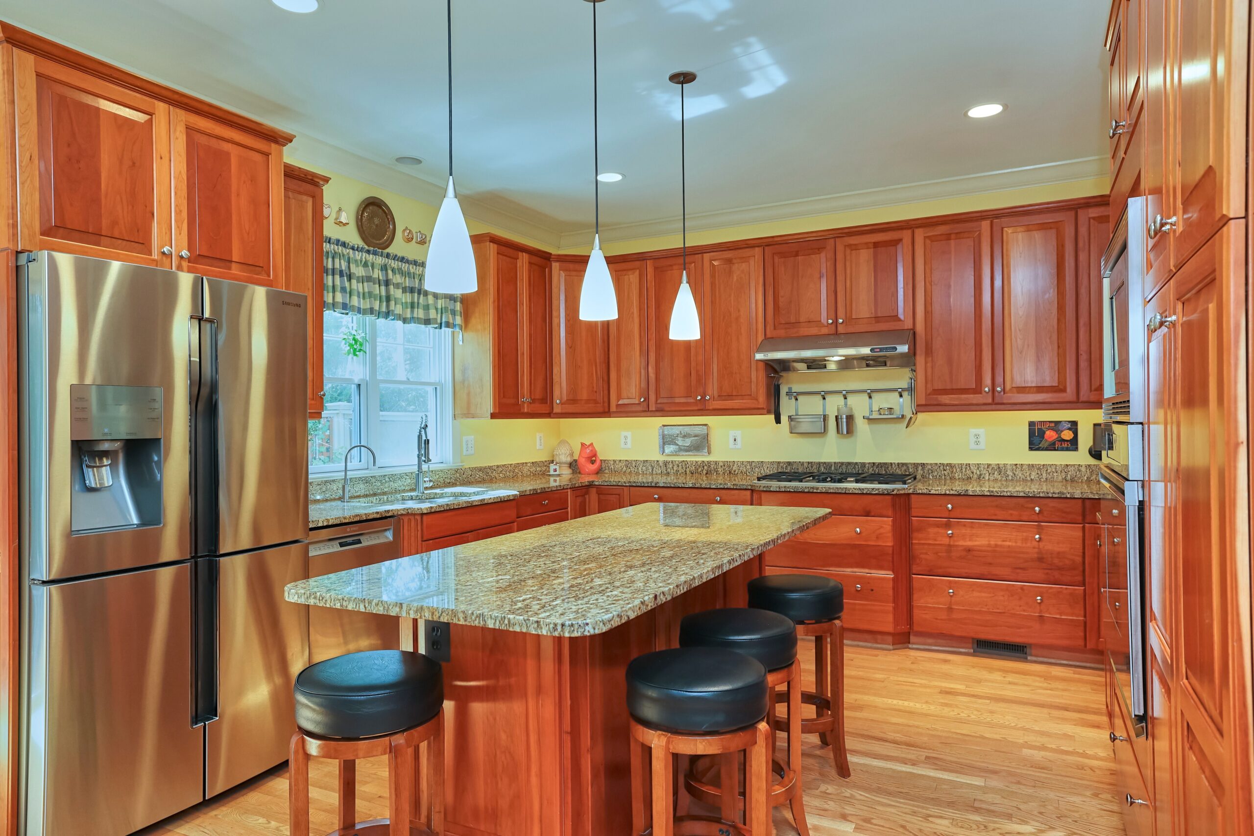 Professional interior photo of 819 N Fillmore St - Showing the kitchen with cherry cabinets, granite counters, hardwood floors, stainless appliances and a large island which can seat 4-5 people
