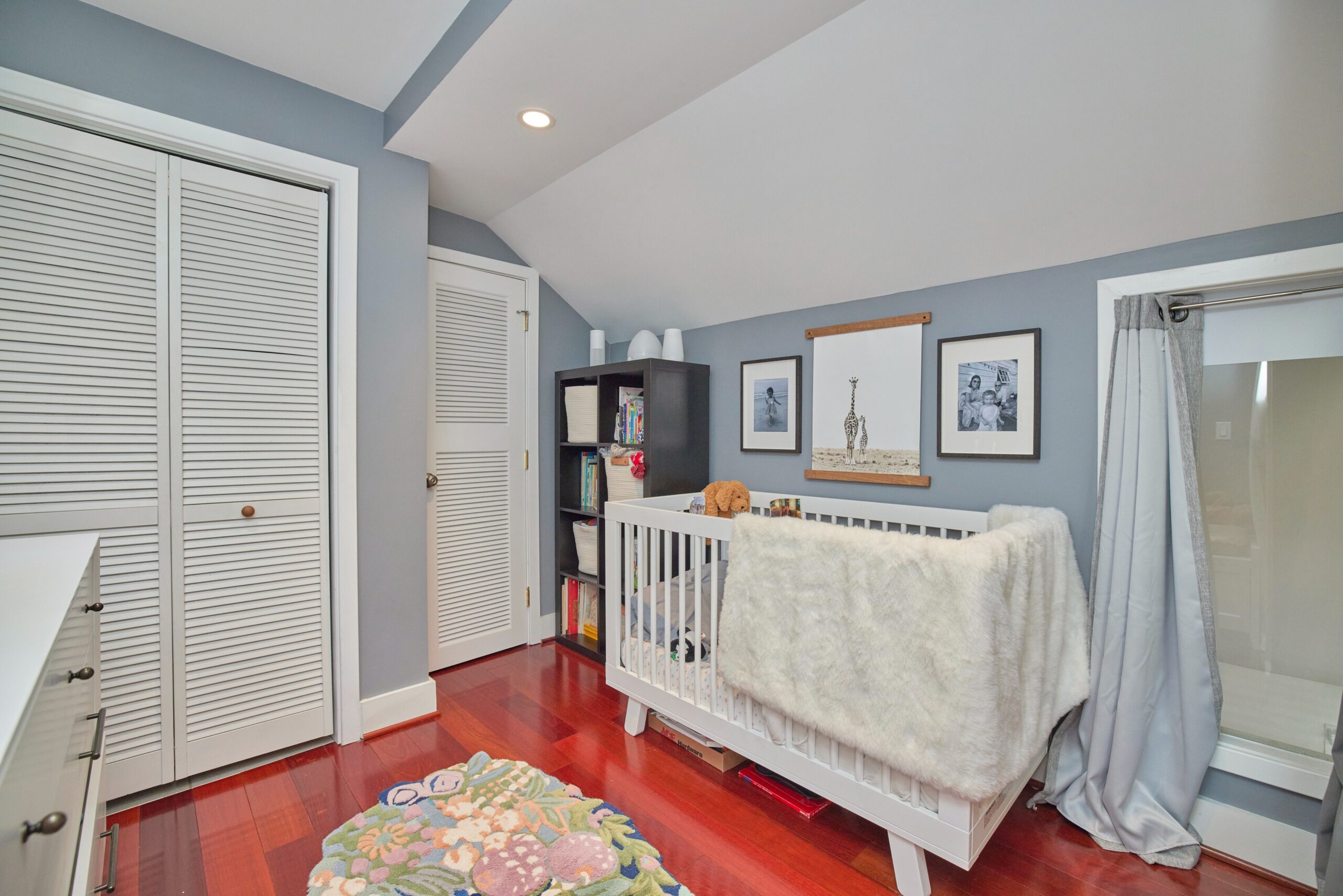 Professional interior photo of 1459 Harvard St NW #6 - showing the loft bedroom which is set as a nursery with angled ceiling and closets