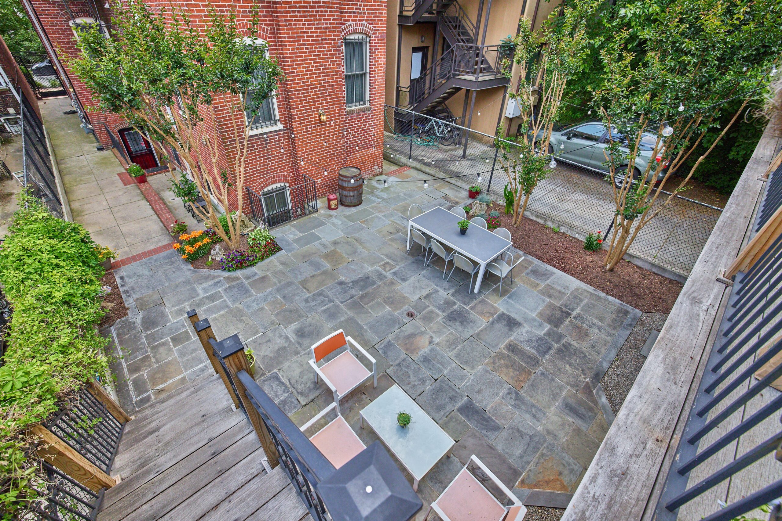 Professional exterior photo of 1459 Harvard St NW #6 - showing the rear of the building from the balcony where the entrance to #6 is looking down into the patio courtyard. 