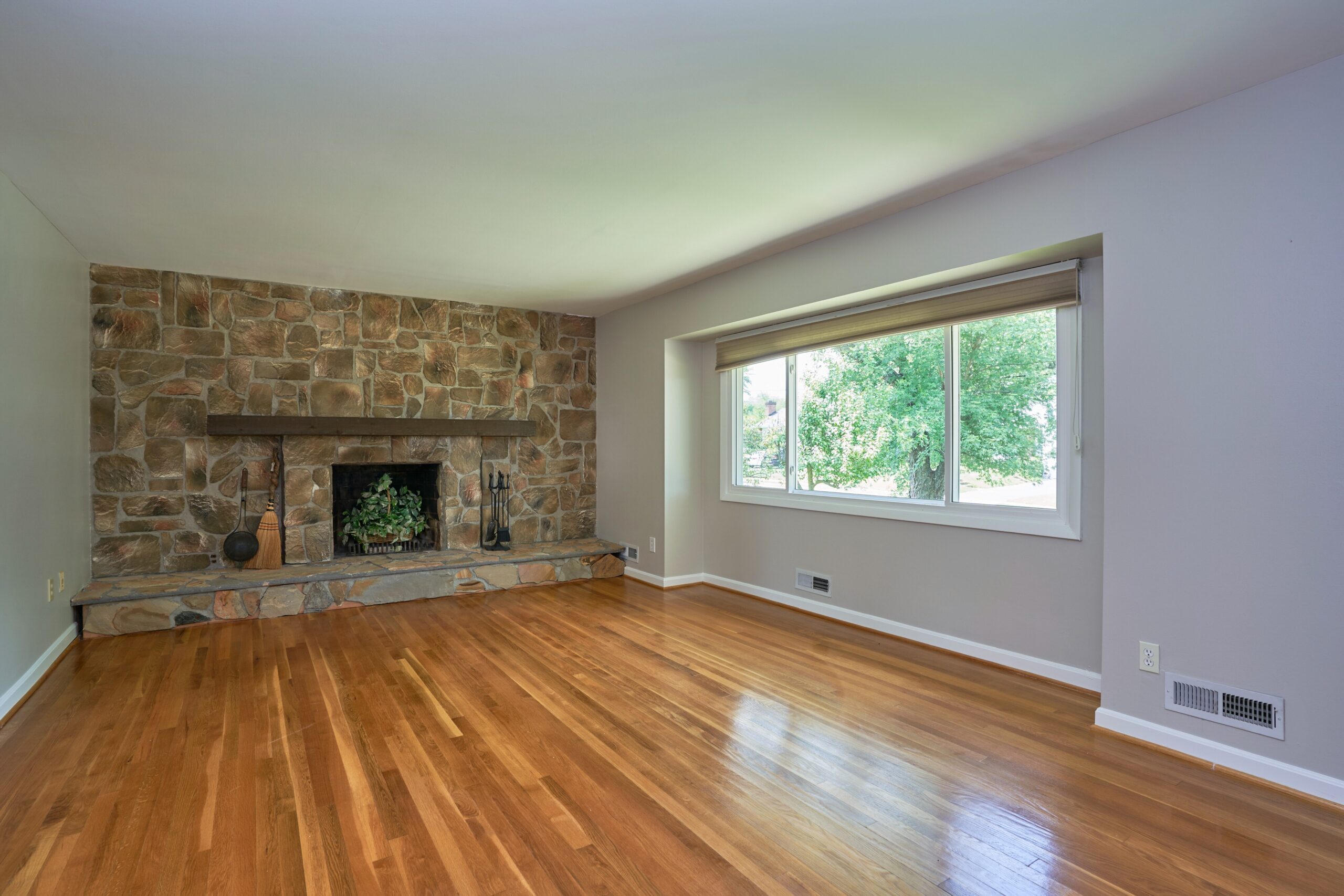 Professional interior photo of 5803 Sable Drive, Alexandria, VA - showing the formal living room with fireplace built into wall to wall stone. hardwood floors