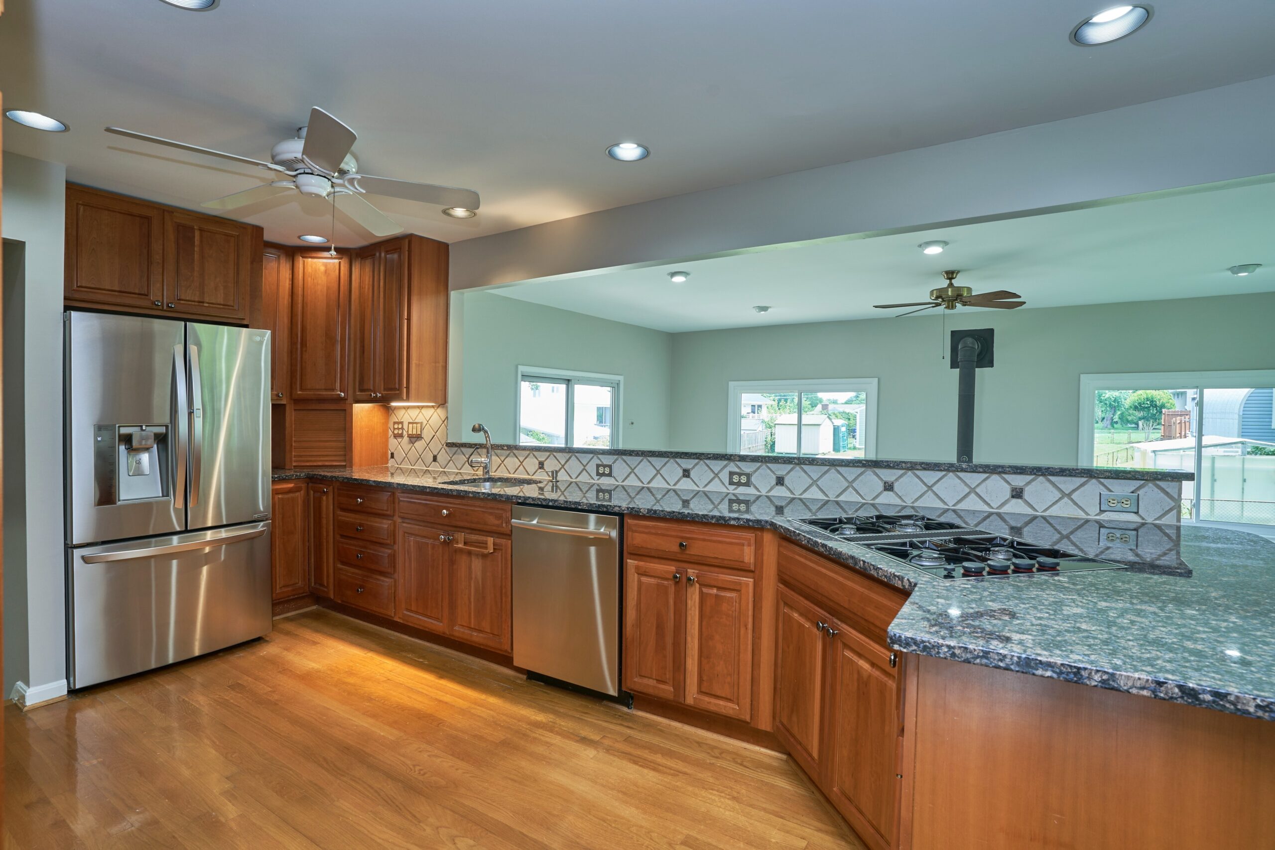 Professional interior photo of 5803 Sable Drive, Alexandria, VA - showing the kitchen with cherry cabinets, granite counters, large stainless appliances, and hardwood floors