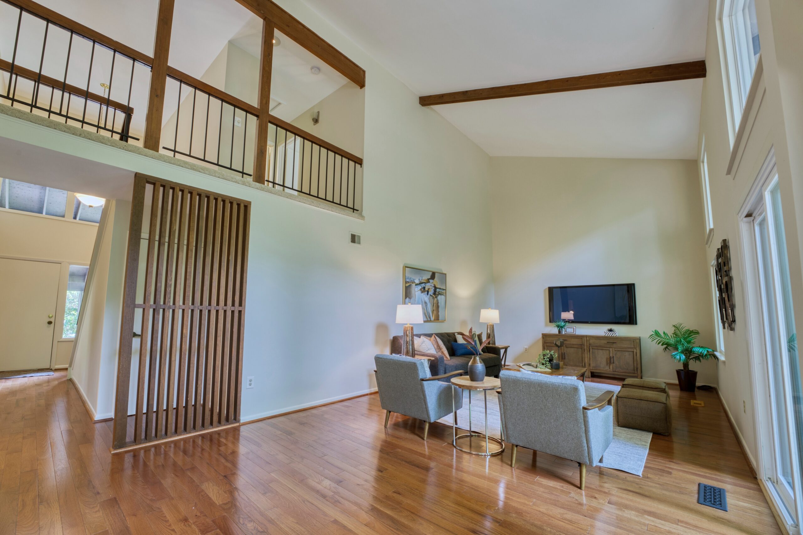 Professional interior photo of 5222 Bradfield Dr in Burke, Virginia - showing the main living room with vaulted ceilings and hardwood floors, wood accents and a wall of windows