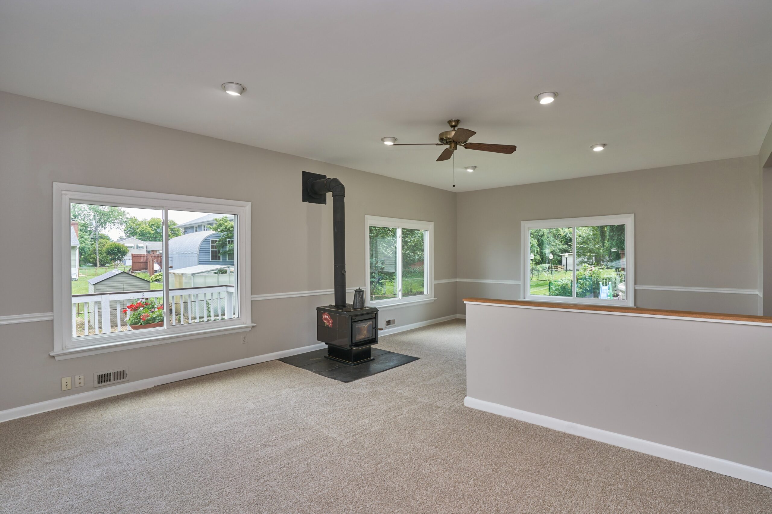 Professional interior photo of 5803 Sable Drive, Alexandria, VA - showing the recessed living room which is a step down from the kitchen in the rear addition. The woodstove is visible and a half-height partition divides the large space