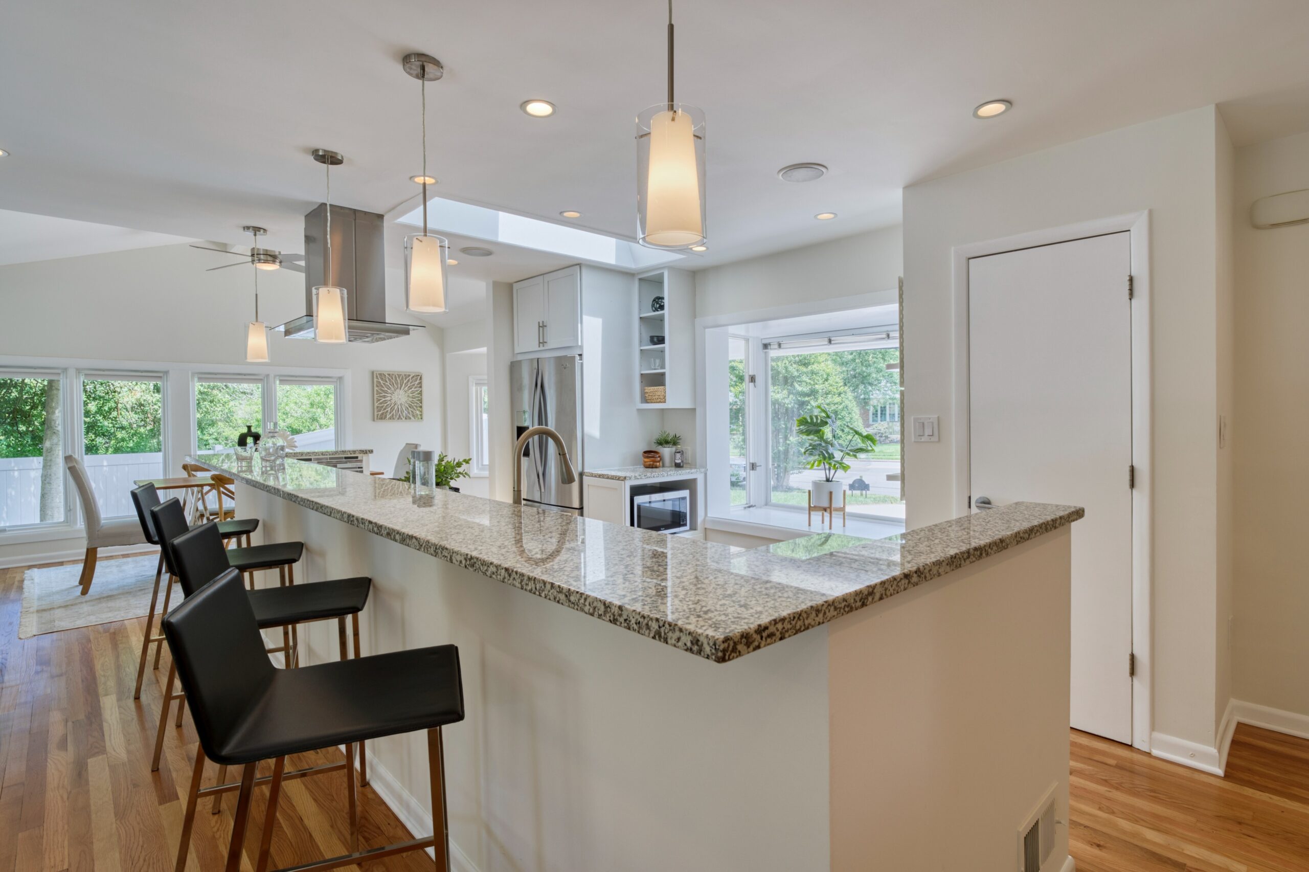 Professional interior photo of 8320 Fort Hunt Rd, Alexandria - showing the open kitchen with skylight, huge two-tier island with range and stainless hood