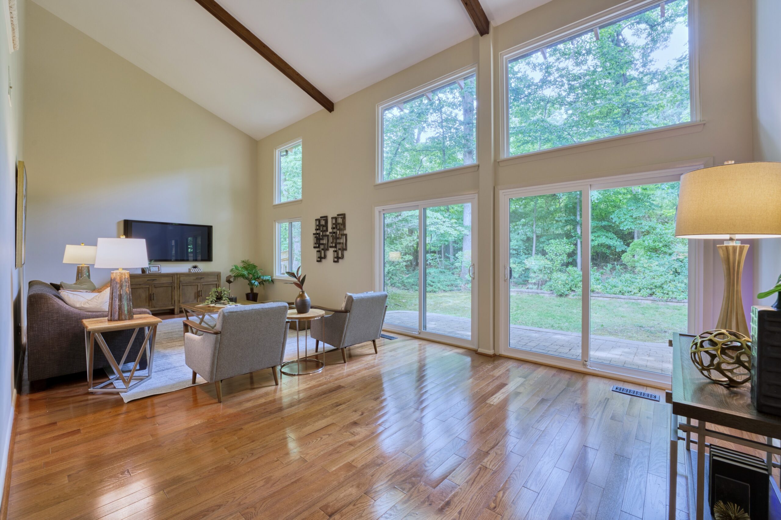 Professional interior photo of 5222 Bradfield Dr in Burke, Virginia - showing the main living room with vaulted ceilings and hardwood floors, wood accents and a wall of windows