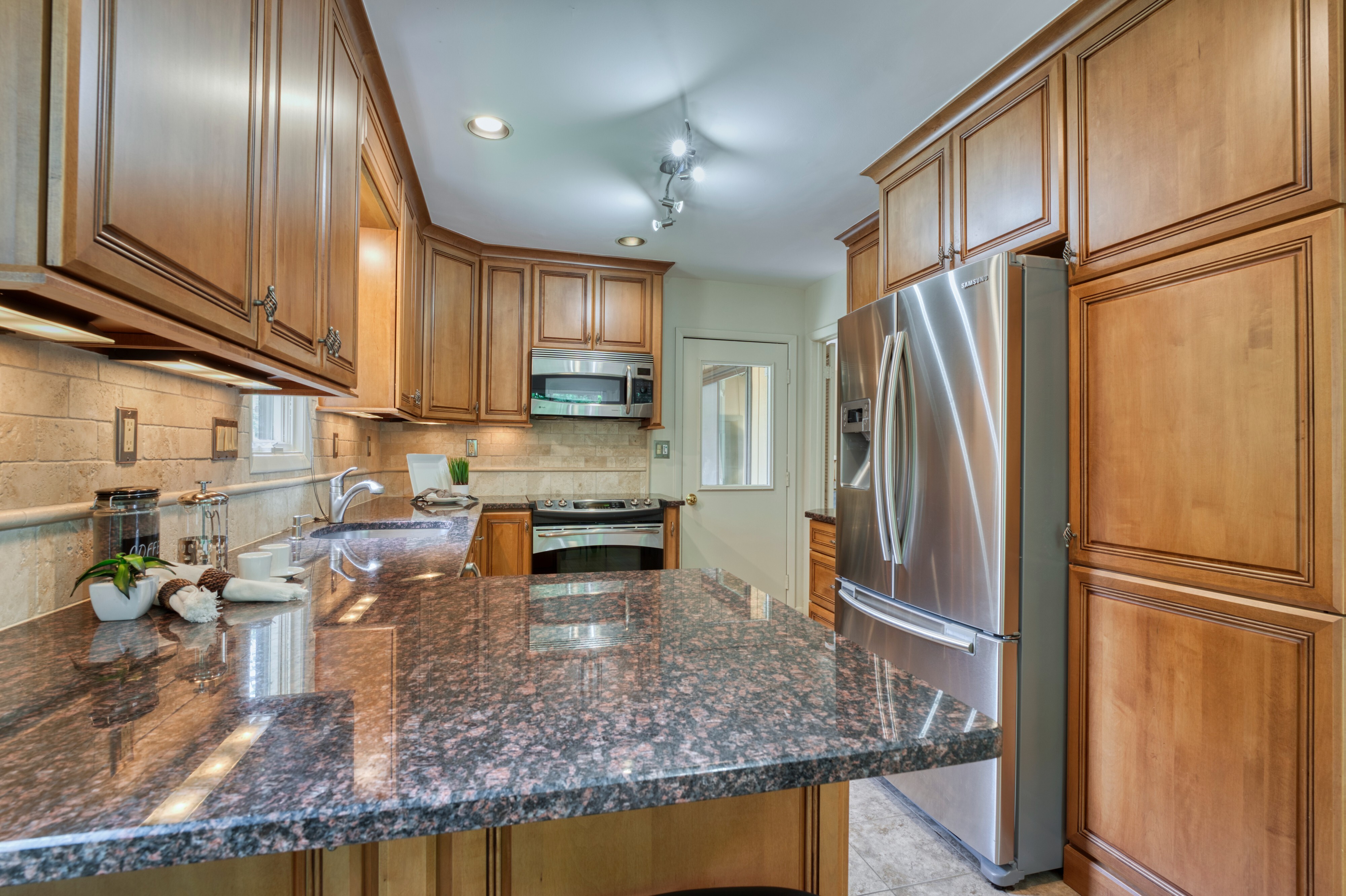 Professional interior photo of 5222 Bradfield Dr in Burke, Virginia - showing the kitchen with walnut cabinets and grey stone countertops and stainless appliances