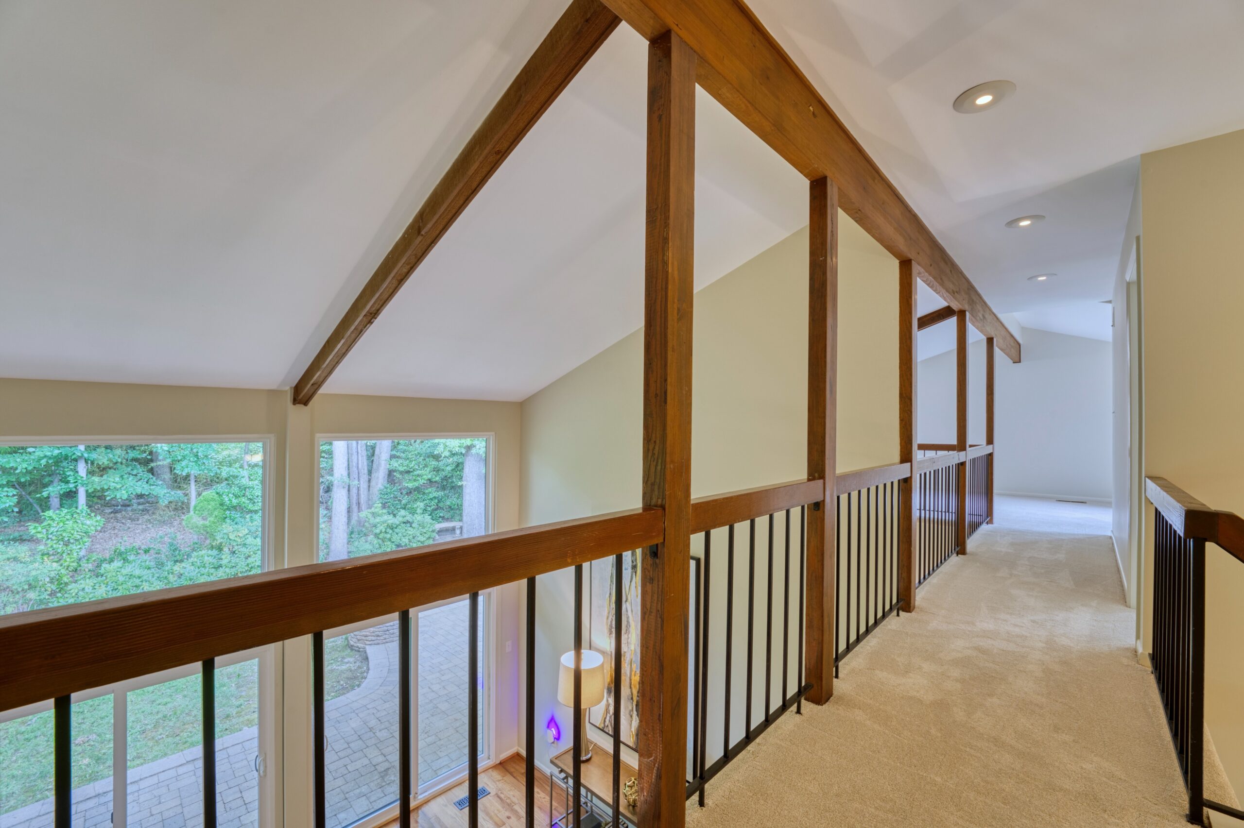 Professional interior photo of 5222 Bradfield Dr in Burke, Virginia - showing the upstairs walkway with wooden rails and ceiling beams looking toward the loft at the end