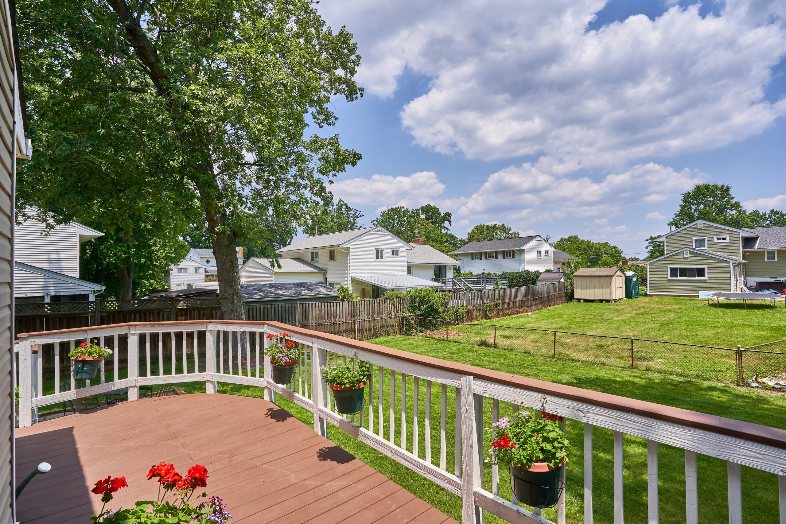 Professional exterior photo of 5803 Sable Drive, Alexandria, VA - showing the view of and from the rear deck over the flat, fully fenced backyard