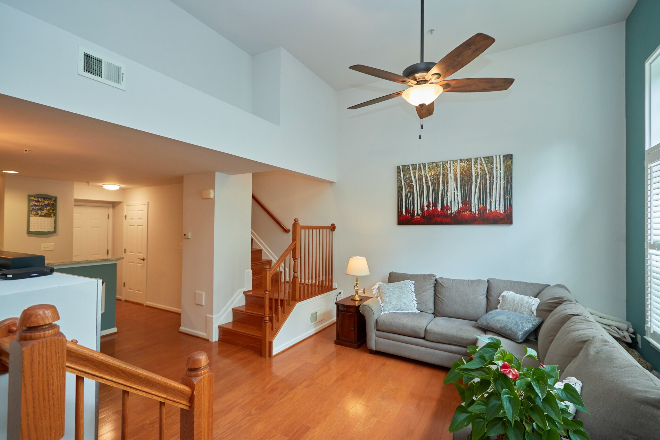 Professional interior photo of 6058 Aster Haven Circle - showing the living room from the front entrance with high ceiling, hardwood floors, staircase to second floor